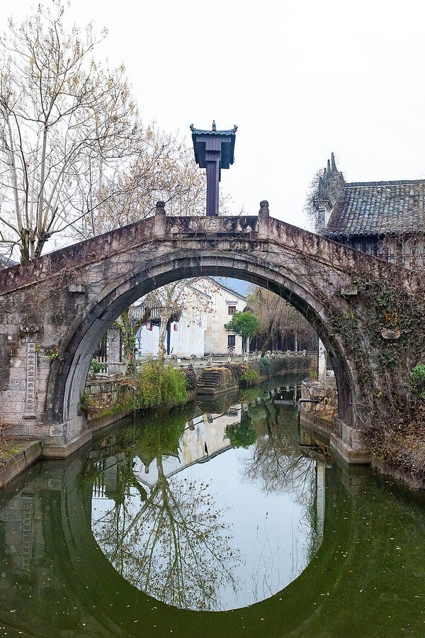 Stone arch bridge reflected in a pond at Dream Valley, Hengdian World Studios, Zhejiang
