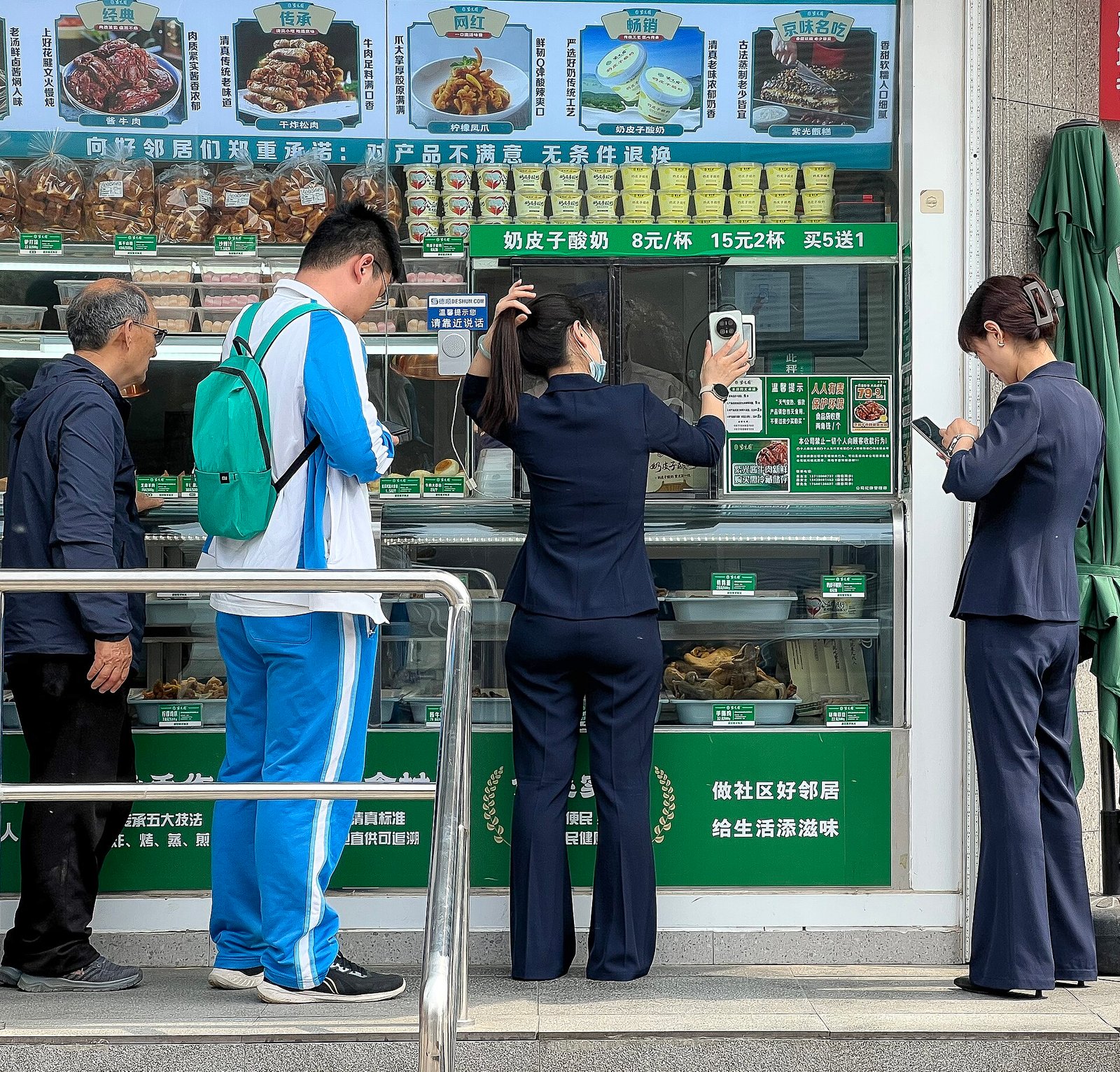 A customer scanning a payment QR code with her phone at a small shop counter in China