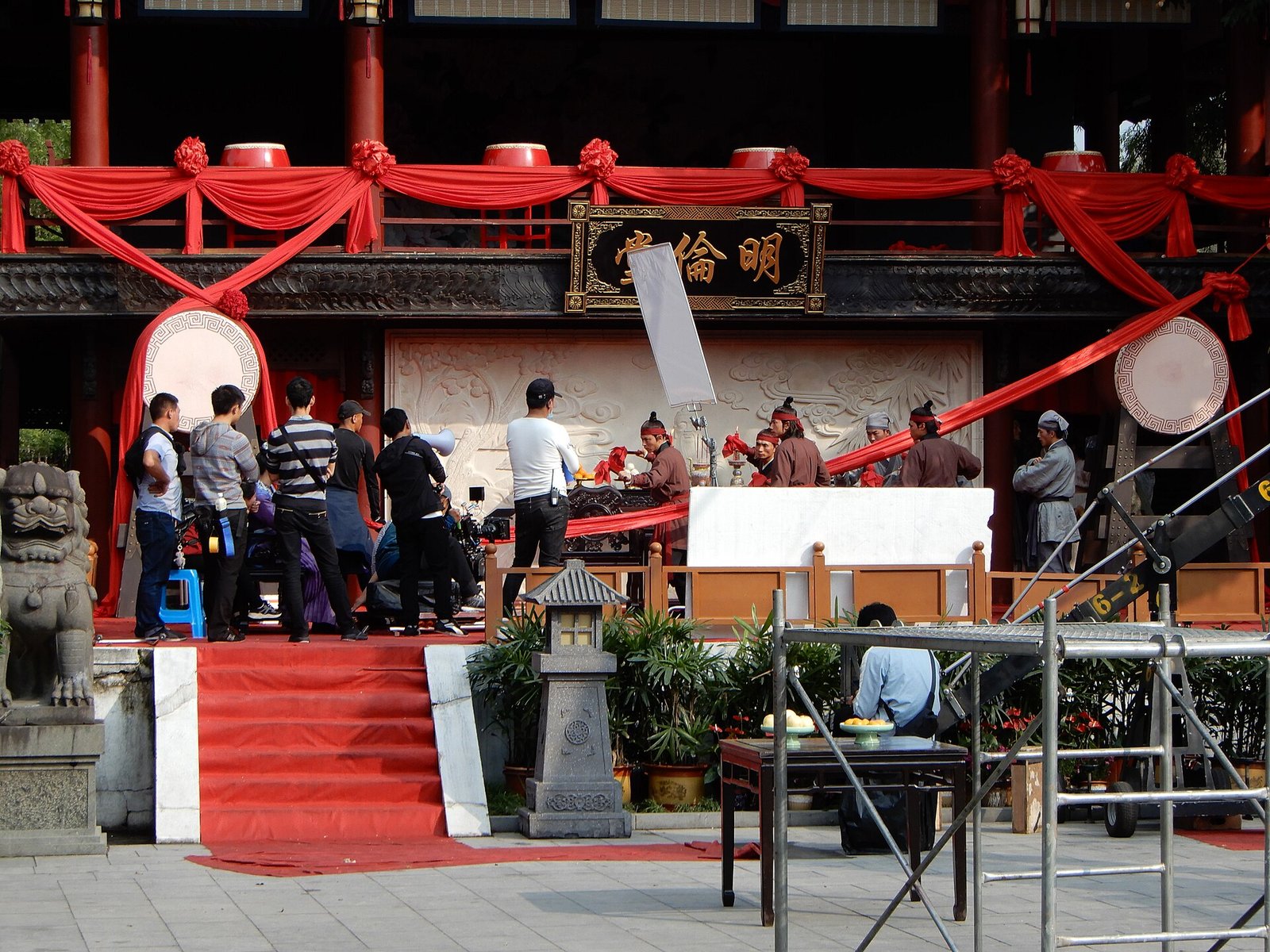 A film crew, cameras and costumed actors shooting a scene on a red-carpeted set at Hengdian World Studios in Zhejiang