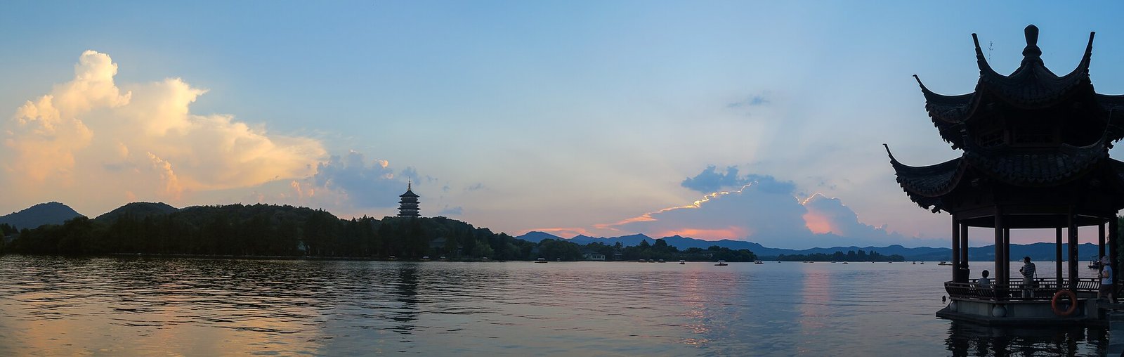 A dusk panorama across West Lake in Hangzhou, with a pagoda on the far shore and a lakeside pavilion in the foreground