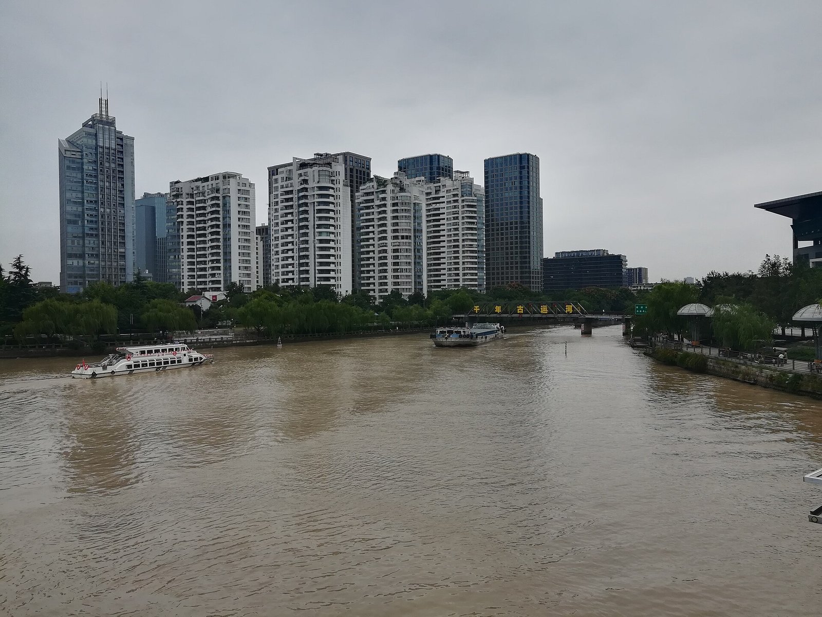Boat traffic on the Beijing-Hangzhou Grand Canal at Wulinmen in central Hangzhou, with the city skyline behind