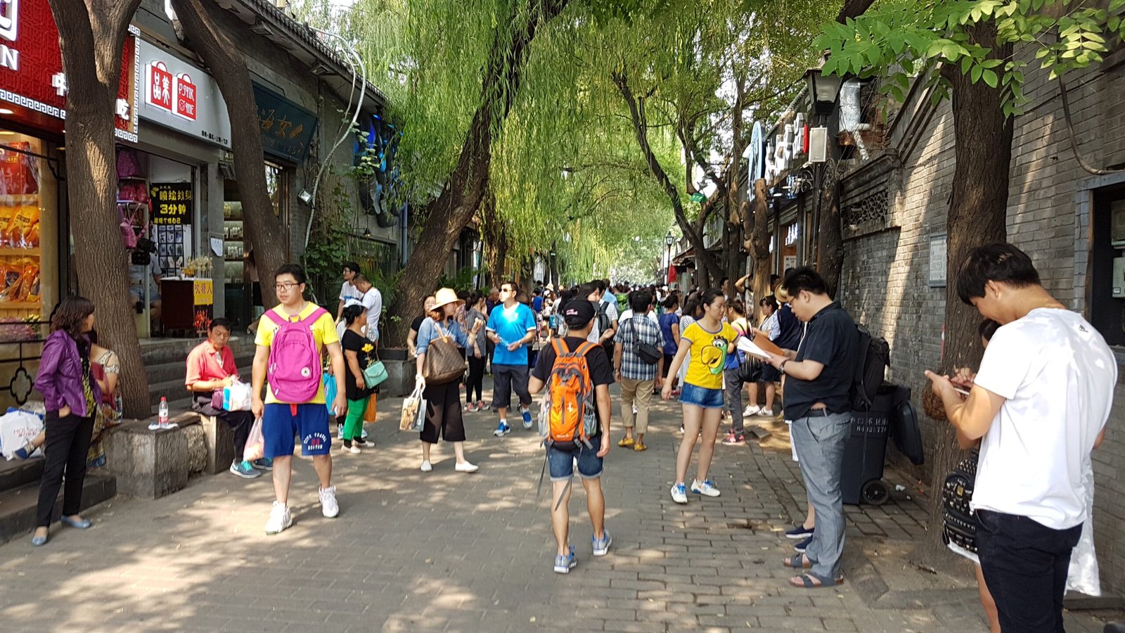 A grey-brick hutong alley lined with shops and courtyard houses in Nanluoguxiang, central Beijing