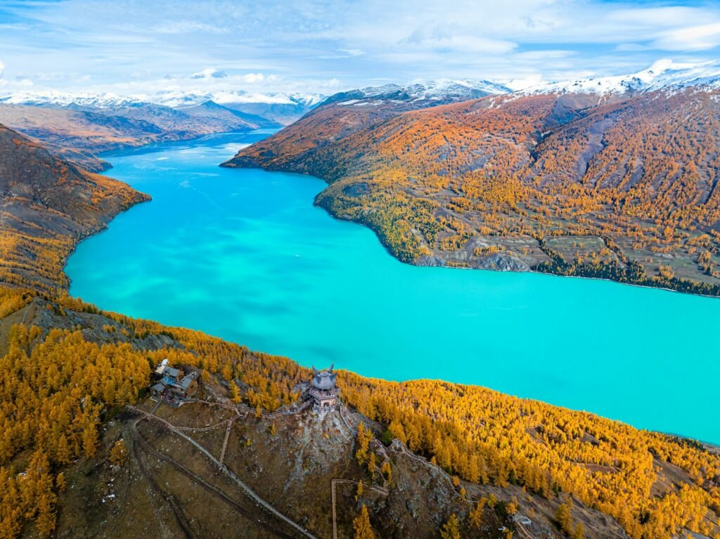An aerial view of a deep blue lake ringed by forested mountains in the Altay range of northern Xinjiang