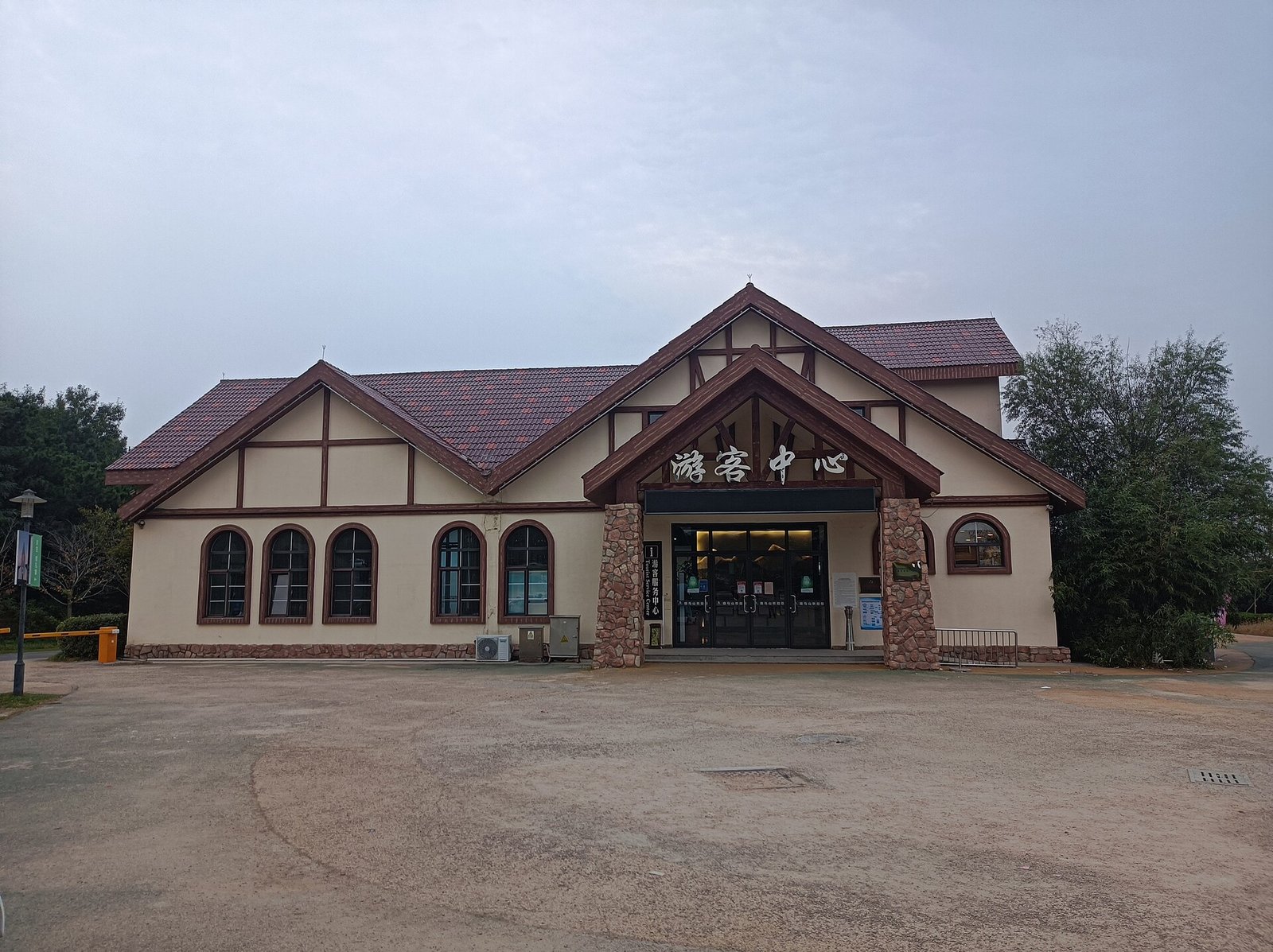 A timber lodge building with a steep pitched roof and a glazed gable, under a soft evening sky