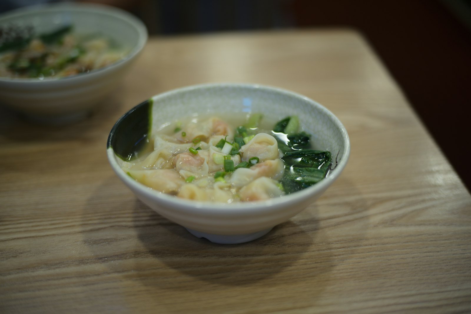 A bowl of Cantonese wonton noodle soup topped with spring onions
