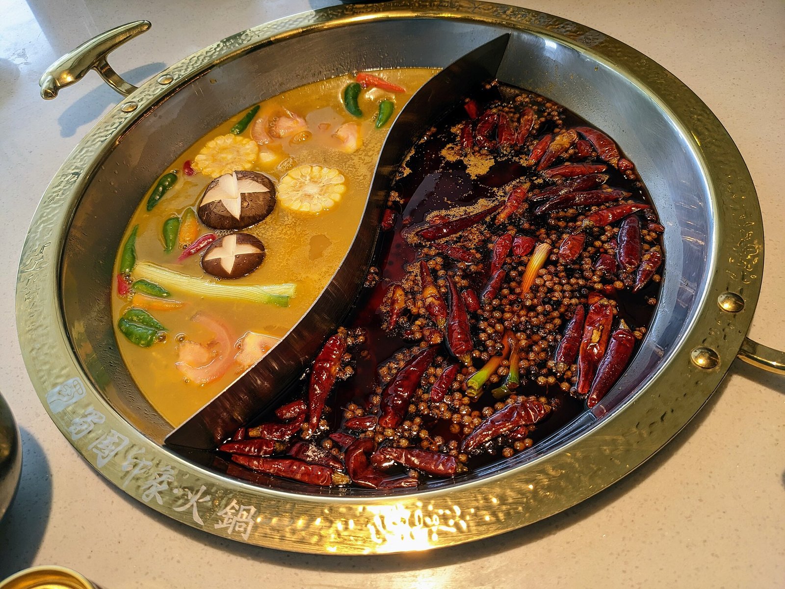 A bubbling Sichuan hotpot with a red chilli broth and side dishes, photographed from above