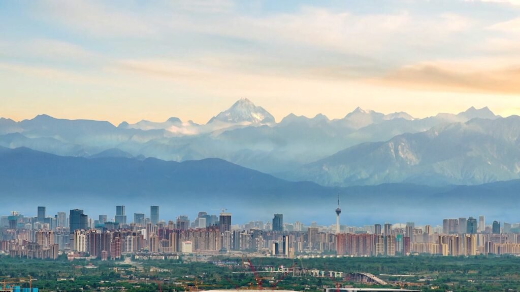The Chengdu skyline at dusk with snow-capped mountains rising behind the city
