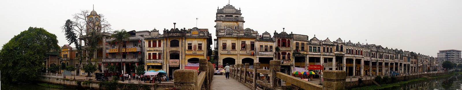 A long panoramic view along a street of two-storey arcaded shophouses with decorative parapets