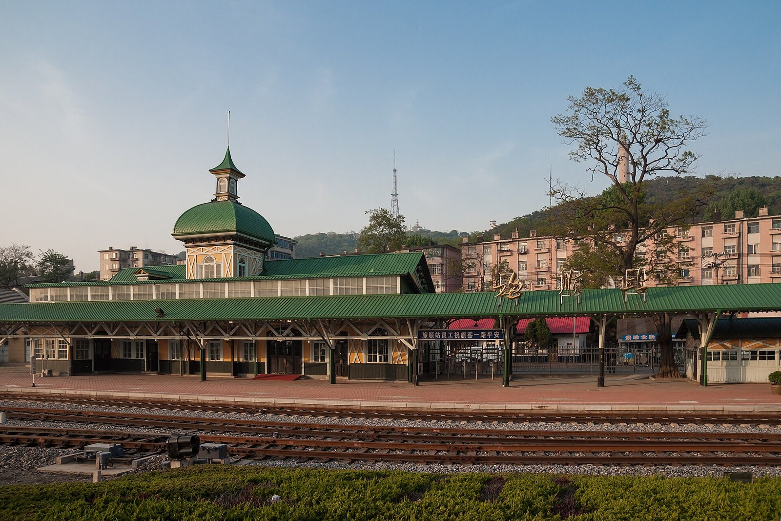The green-domed Russian-era railway station at Lüshun, with a wooded hillside behind and tracks in front