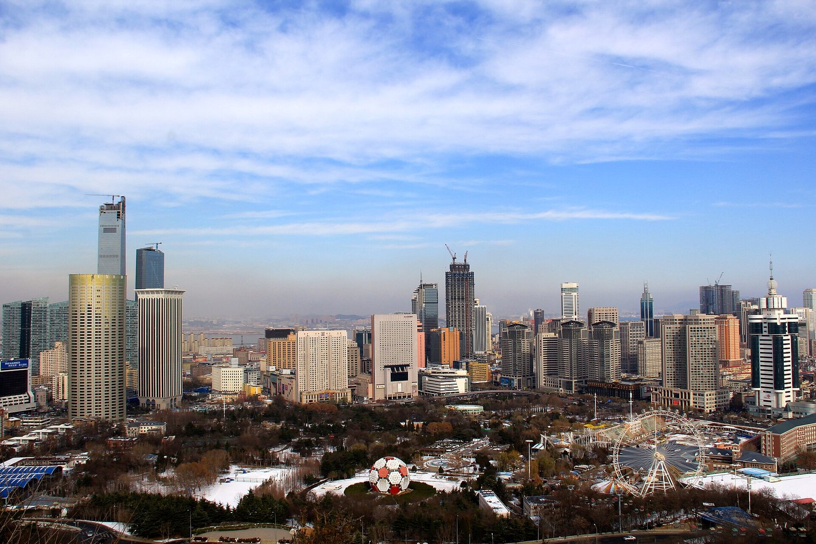 The Dalian skyline seen across the rooftops of the old town, glass towers standing behind low colonial blocks