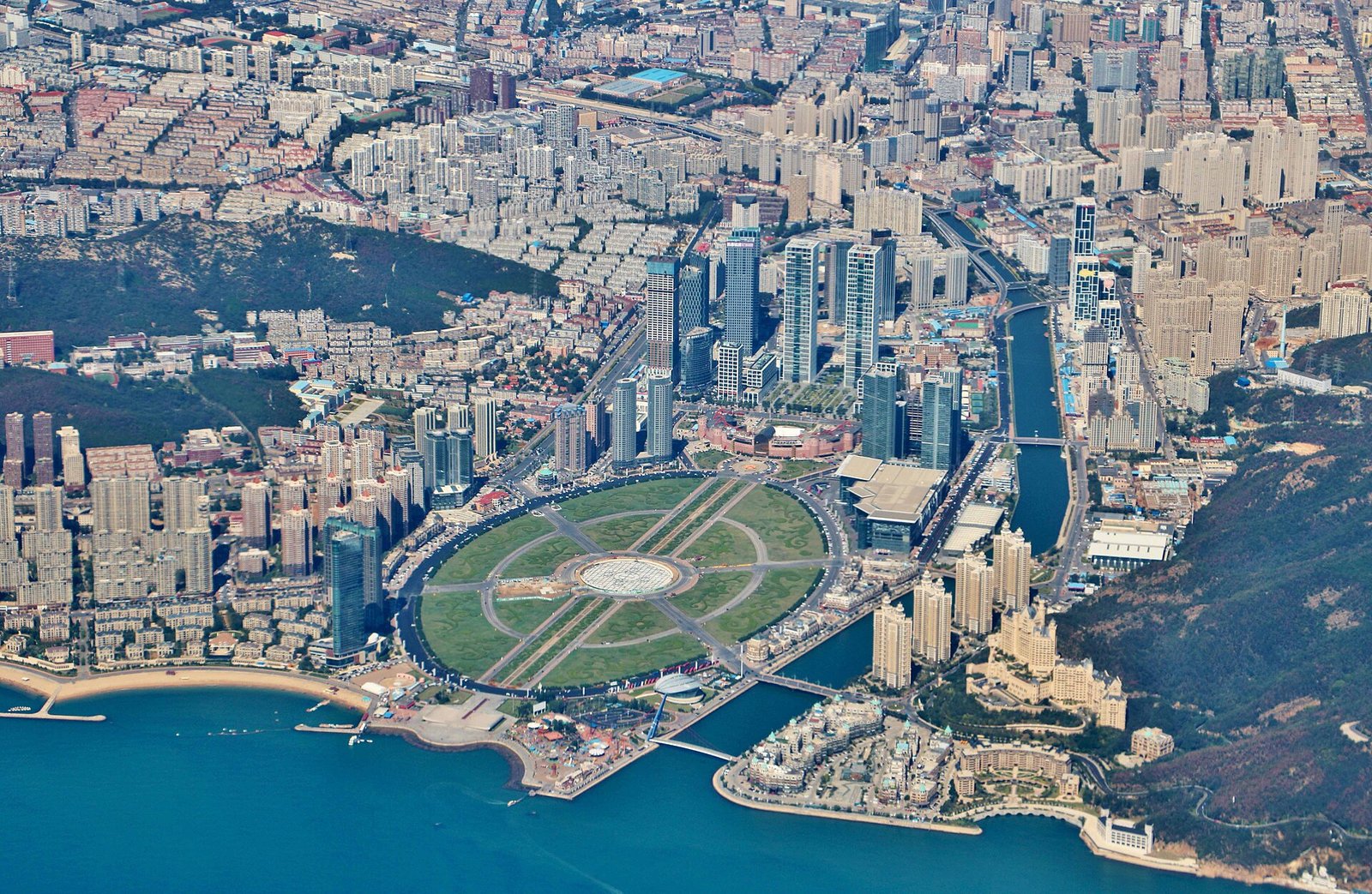 An aerial view of Xinghai Square in Dalian, a vast circular paved plaza on reclaimed land meeting the sea