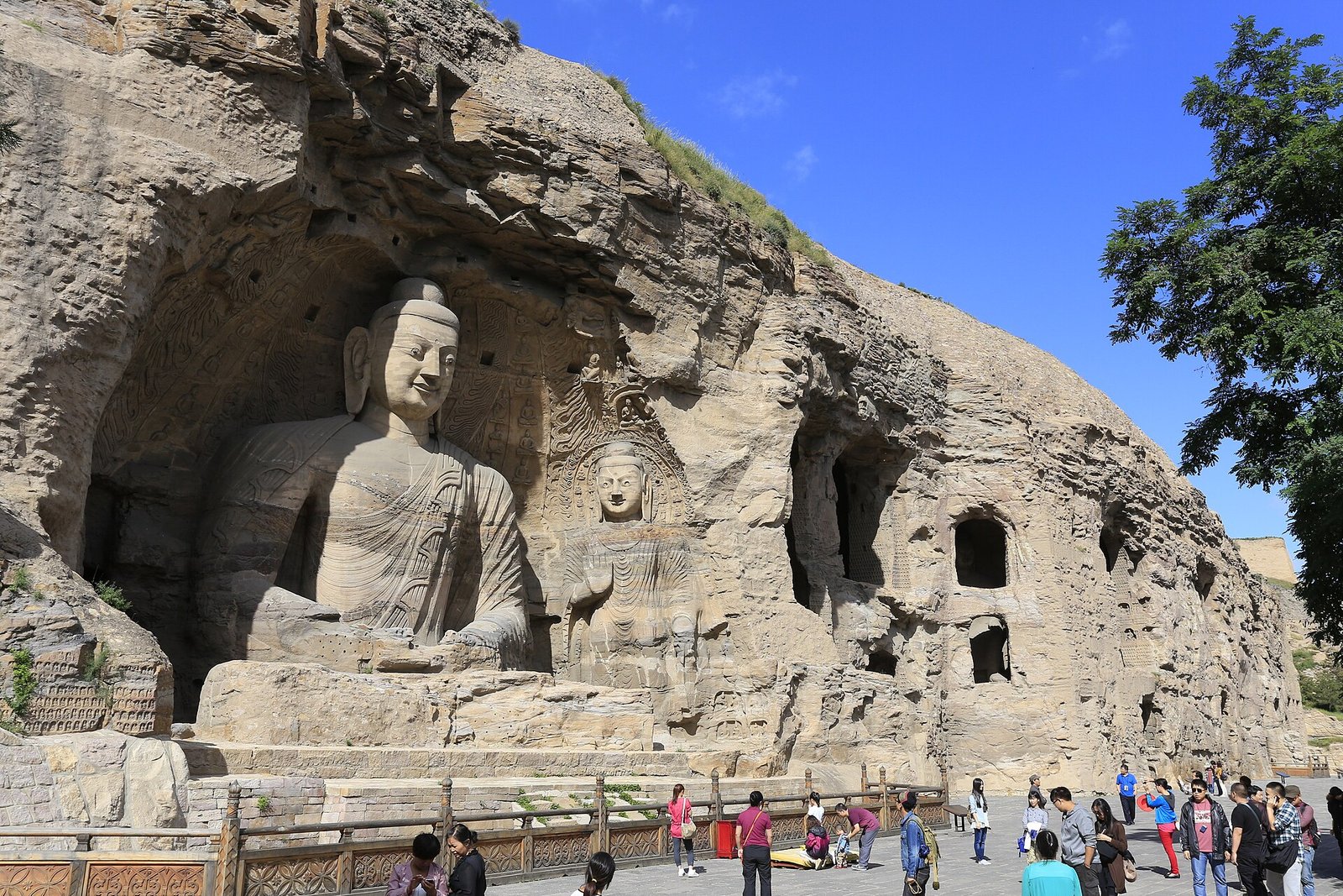 The cliff of carved Buddhas at the Yungang Grottoes near Datong, with visitors on the walkway