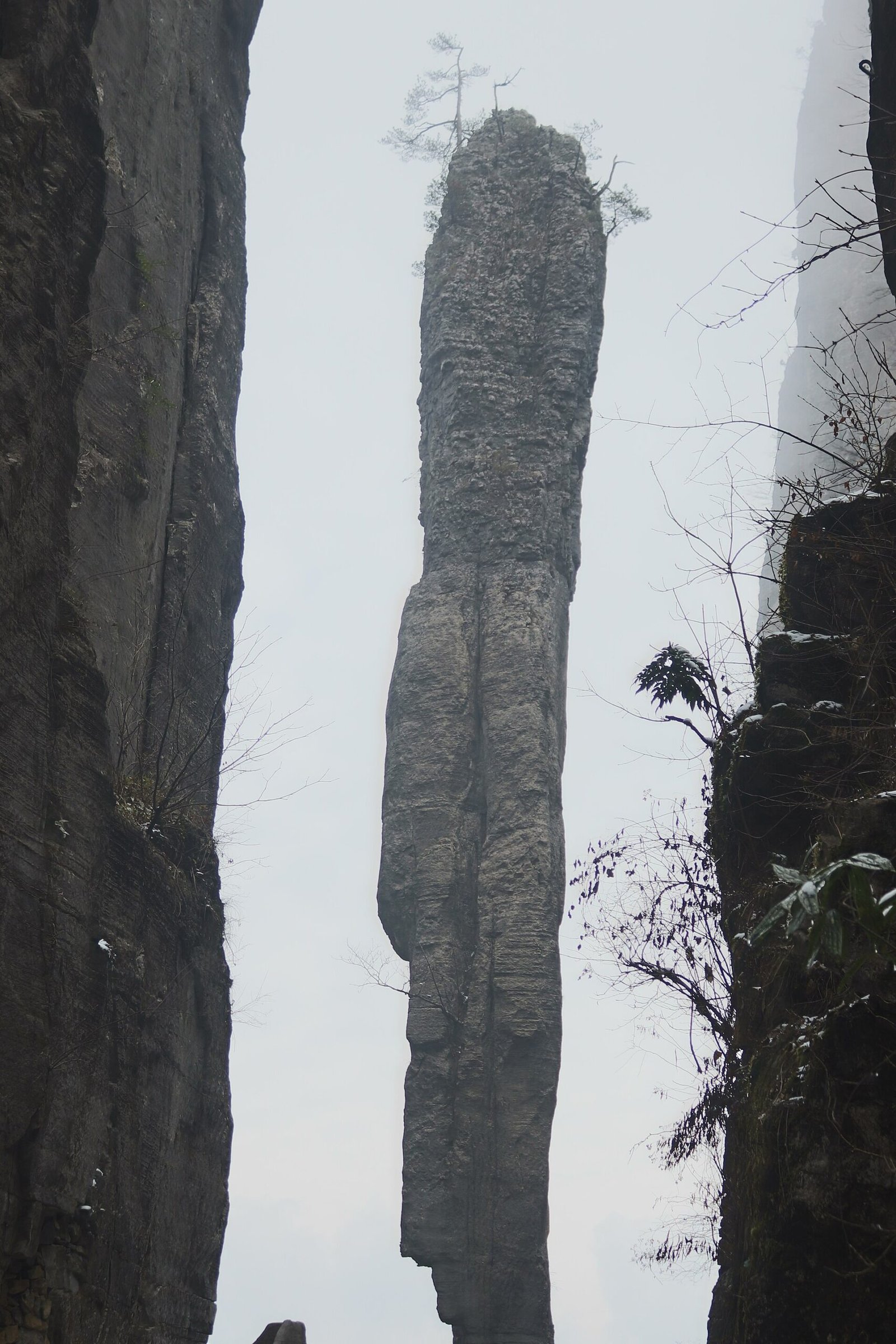 The Yizhuxiang rock pillar at Enshi Grand Canyon, a tall free-standing limestone column silhouetted against mist