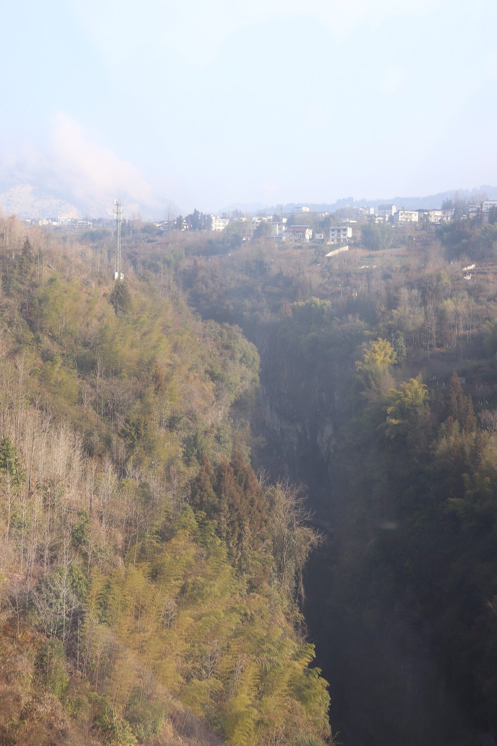 A view down into the Yunlong rift gorge at Enshi Grand Canyon, with the narrow slot cutting through green forest and a river at the bottom