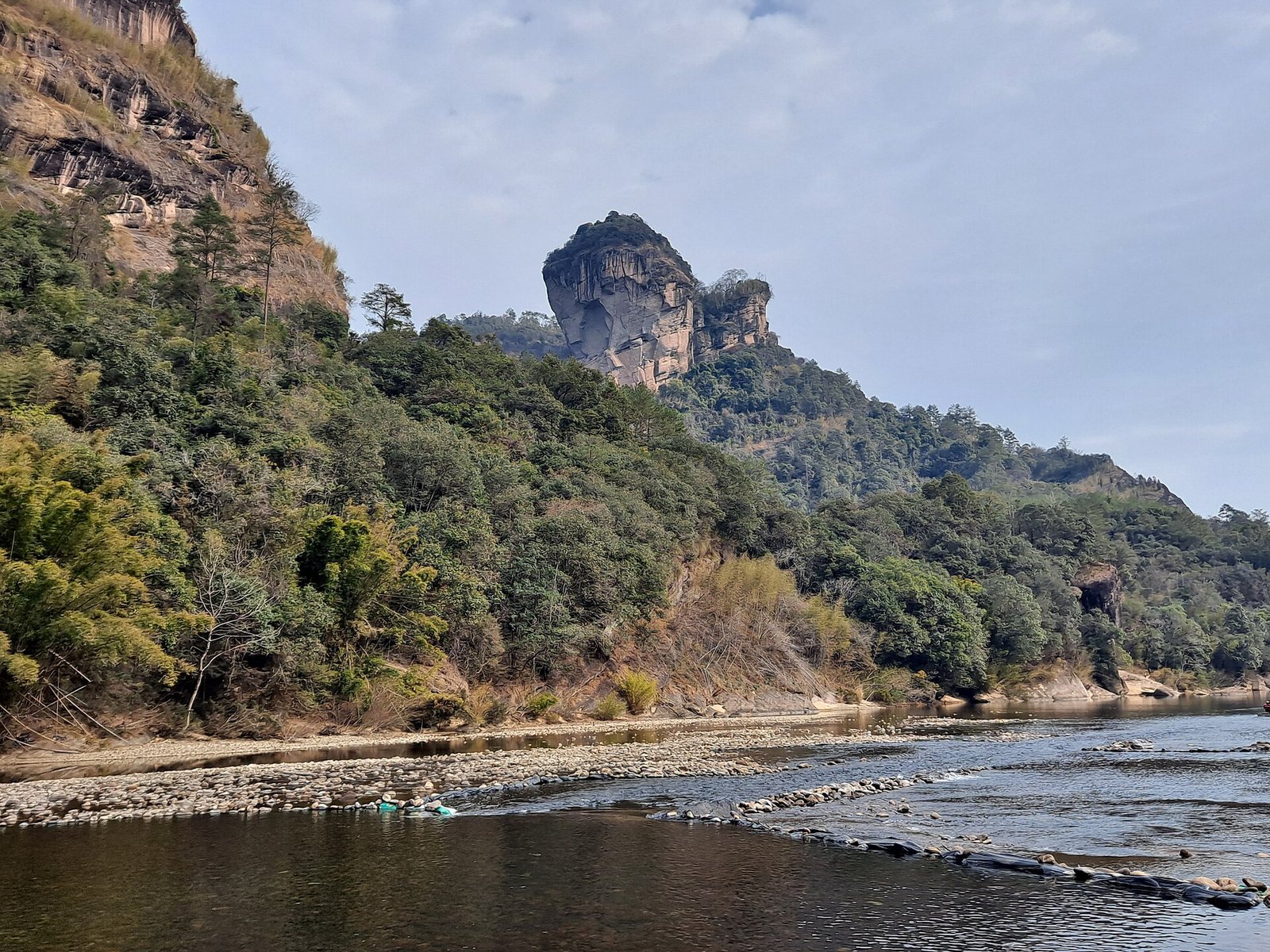 King Peak at Wuyishan rising above a shingle riverbank, with green wooded slopes on both sides