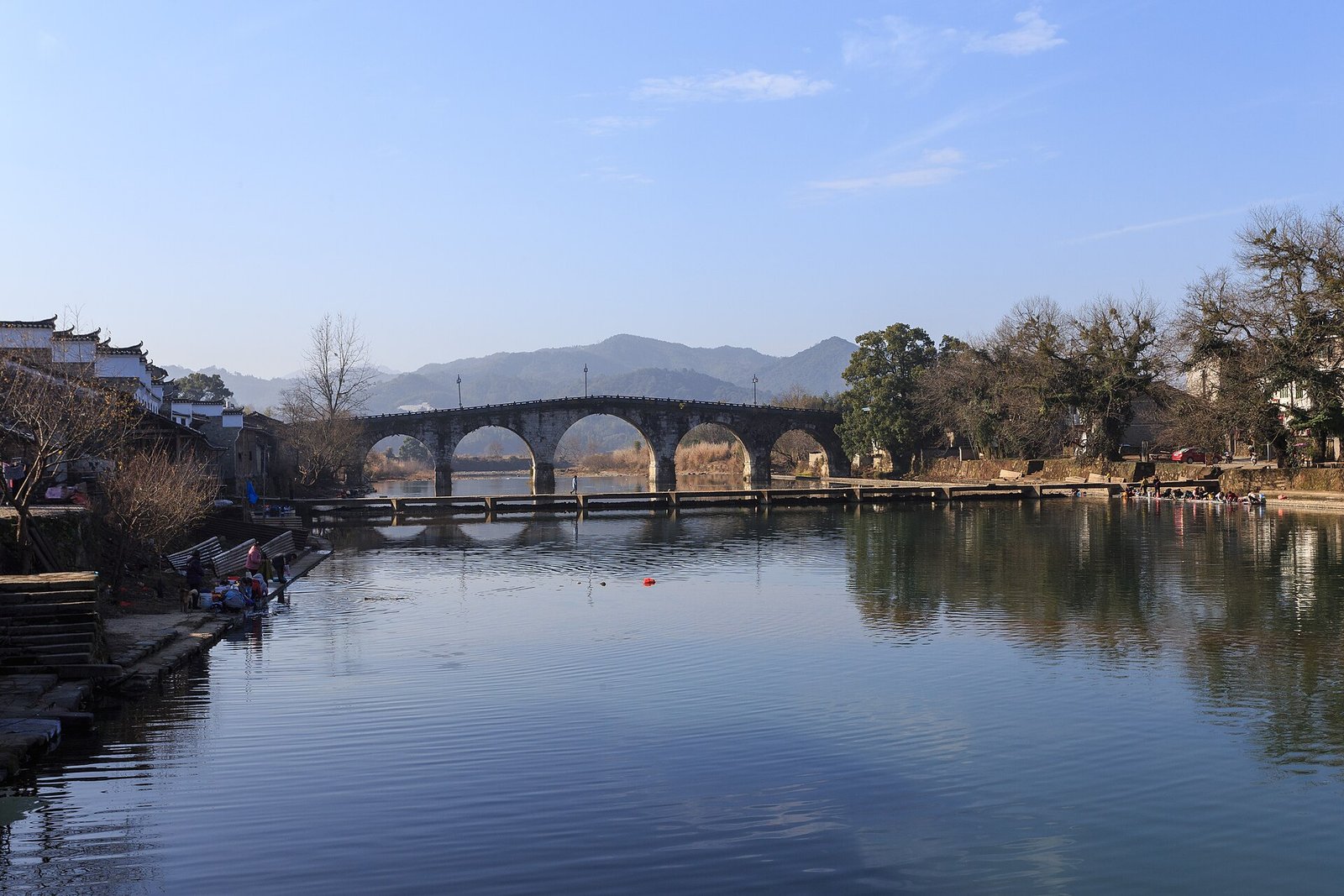 An arched stone bridge crossing a river at Dongbu in Fuliang County, with whitewashed village houses behind