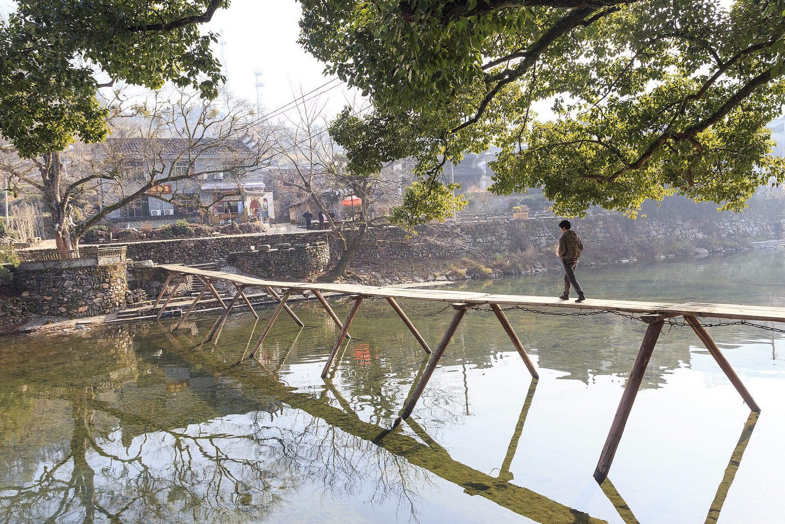 A stone bridge and an old tree over a shallow river at Yaoli in Fuling County, Jiangxi