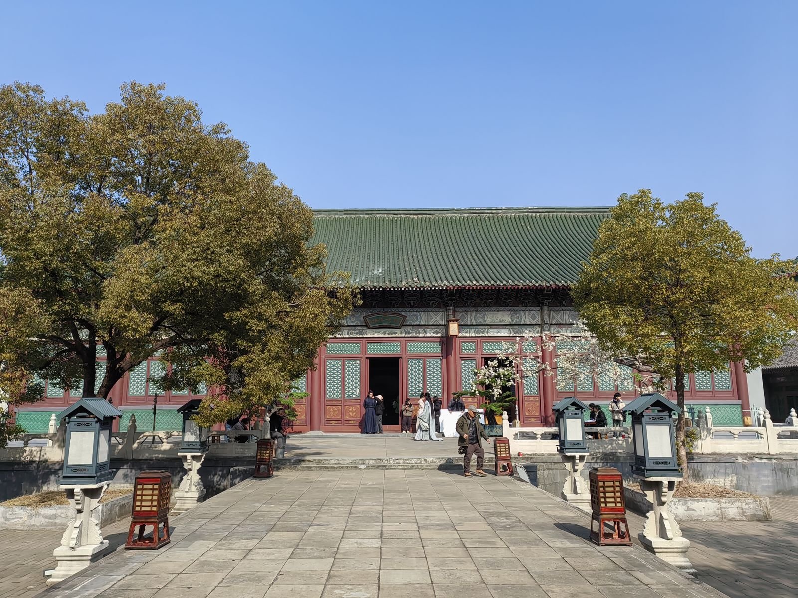 A palace hall with a green glazed roof inside Ming Qing Palace at Hengdian, with visitors in period costume on the terrace
