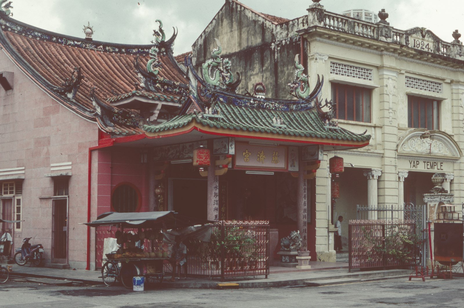 An old Chinese shophouse with weathered wooden doors and a bicycle parked outside