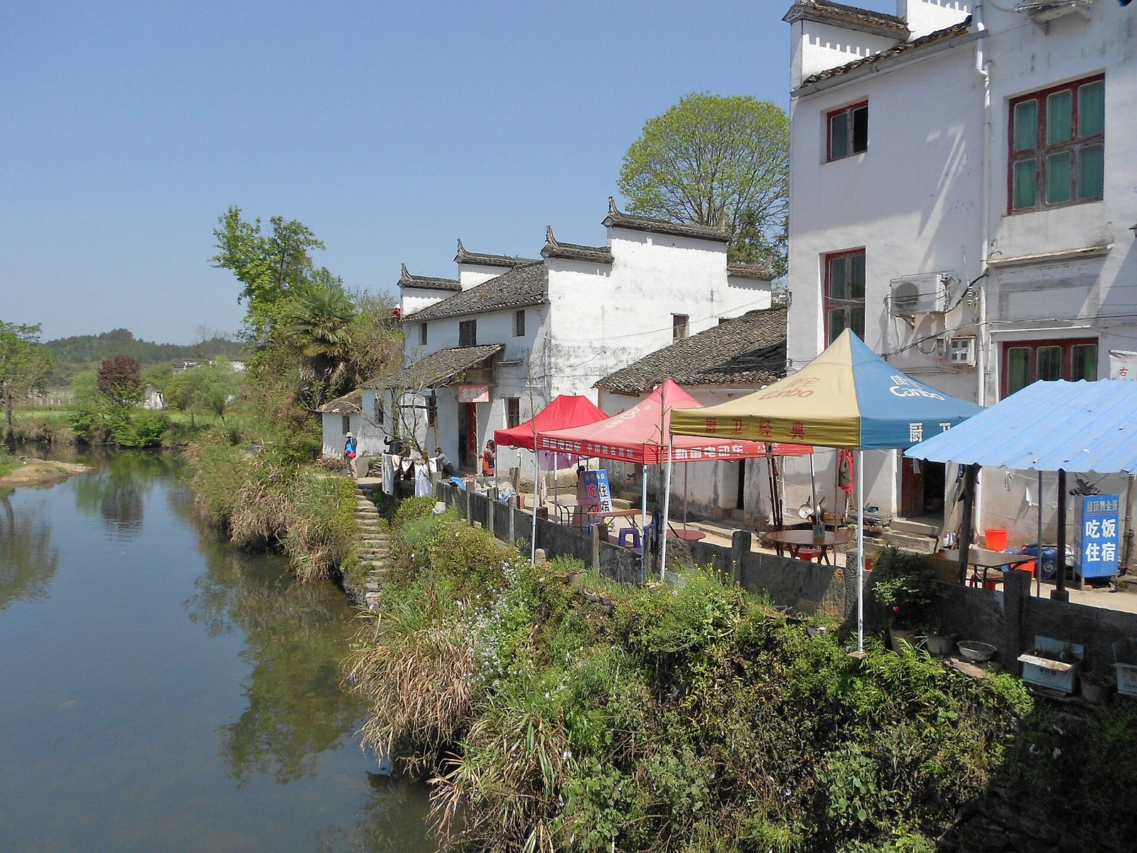 The riverside frontage of Sixi village in Wuyuan, with Huizhou houses and umbrellas along the bank