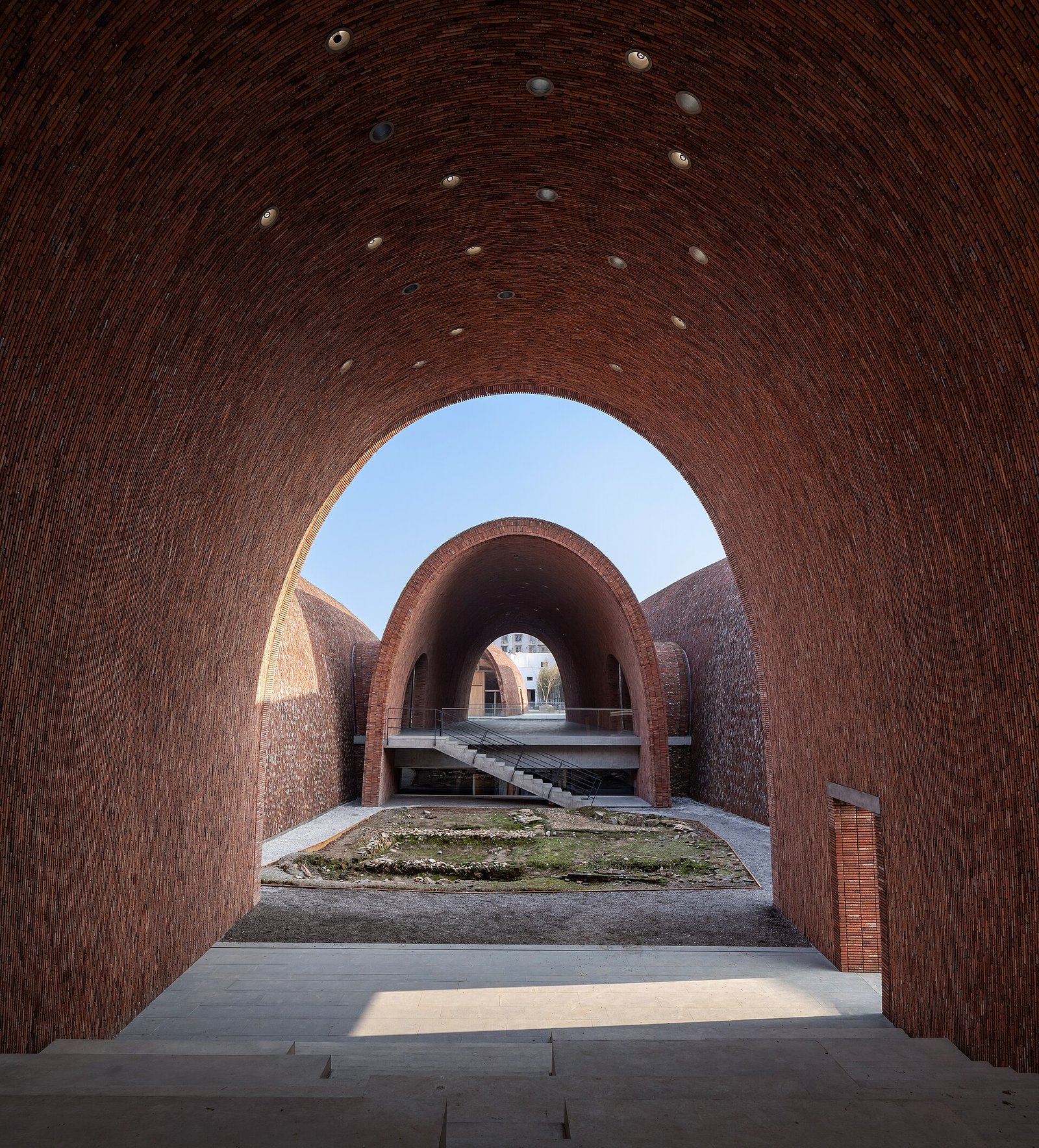 Looking through a series of brick arches inside the Jingdezhen Imperial Kiln Museum toward a courtyard