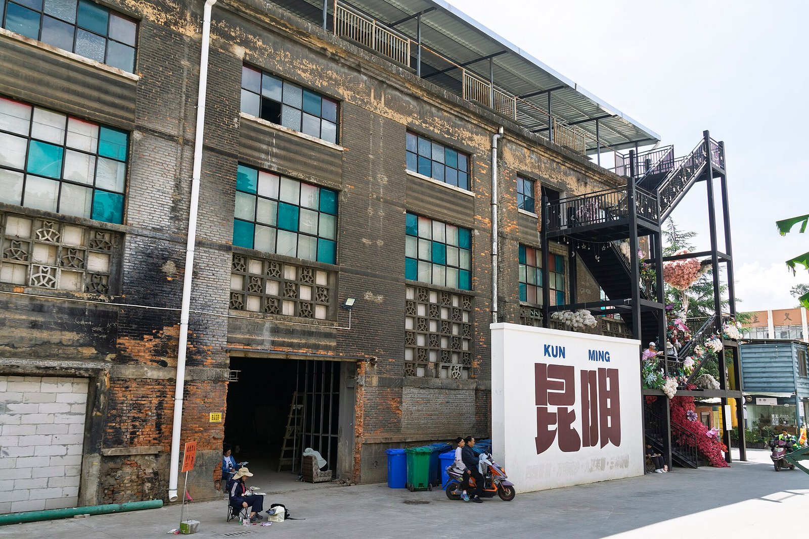An old brick factory building in Kunming with tall grid windows, now part of an industrial-heritage cultural quarter