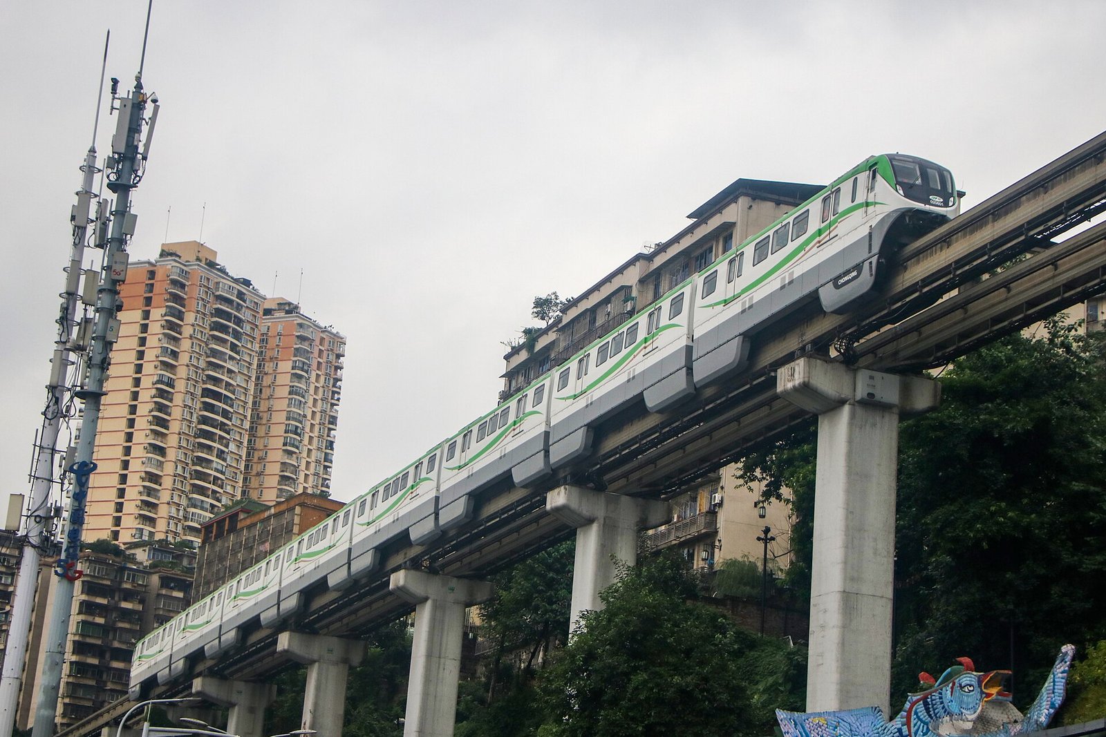 A Chongqing Rail Transit Line 2 monorail train arriving at Liziba Station, passing through the middle of a residential building