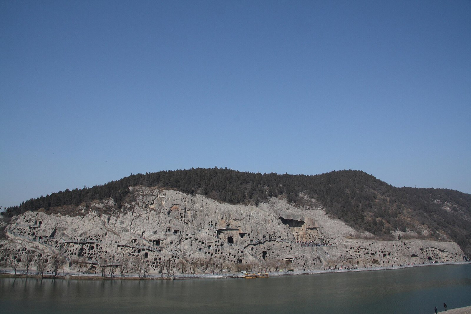 The cliff of the Longmen Grottoes seen across the Yi River at Luoyang, its caves cut into the limestone hillside