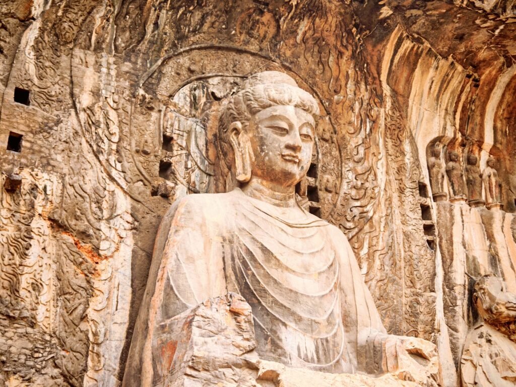 The giant Vairocana Buddha of Fengxian Temple at the Longmen Grottoes, Luoyang, lit by warm afternoon light