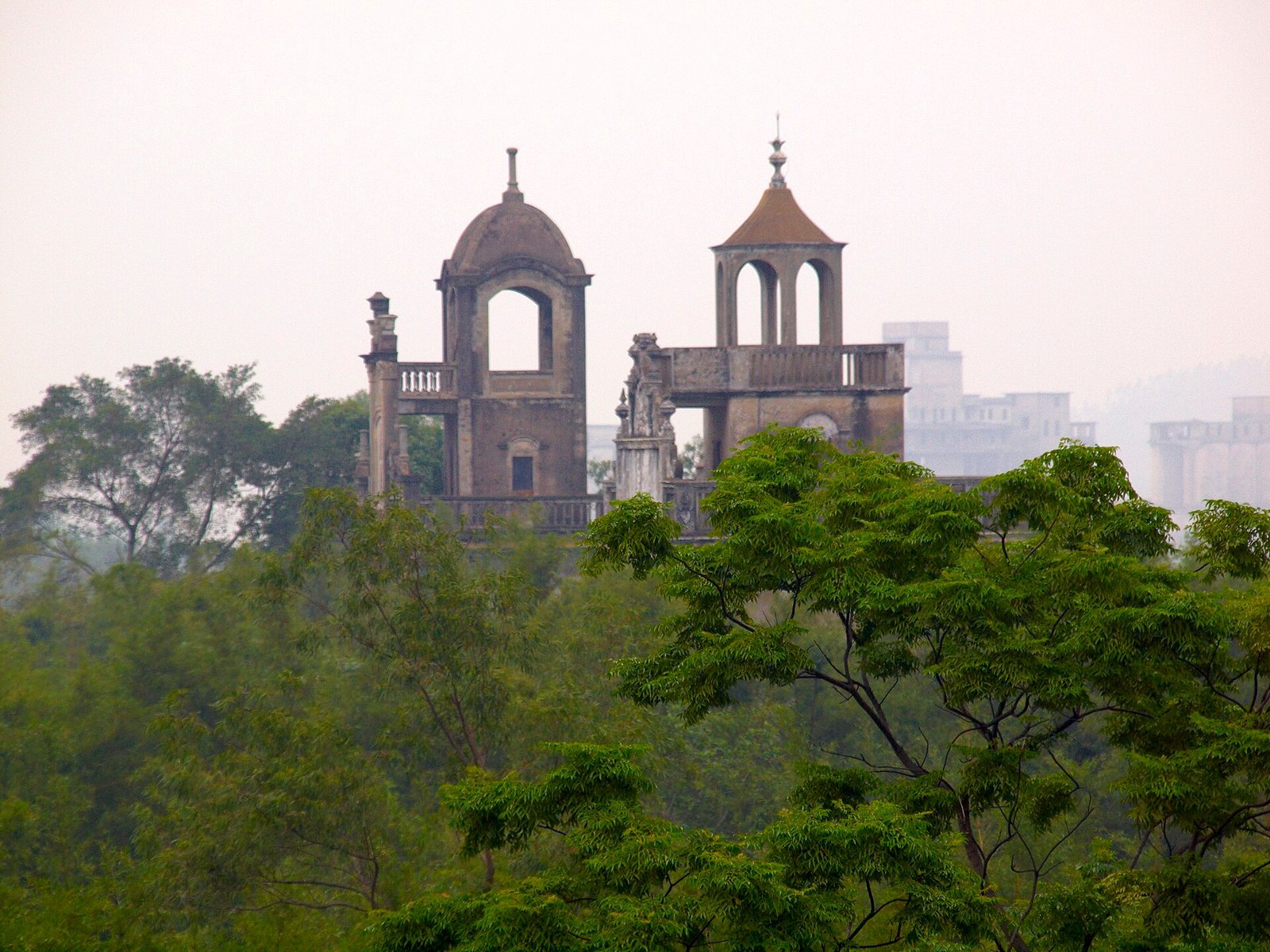 Three fortified towers rising above dense bamboo and trees, with a river visible beyond them