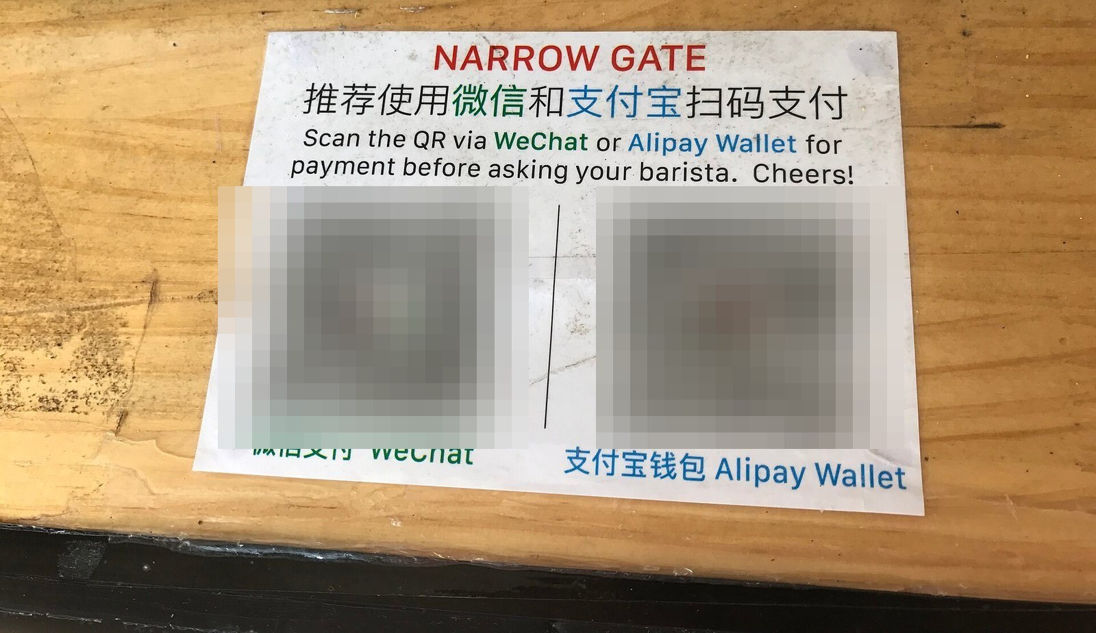 A shop sign showing side-by-side WeChat Pay and Alipay QR codes with English instructions, the standard way to pay in China