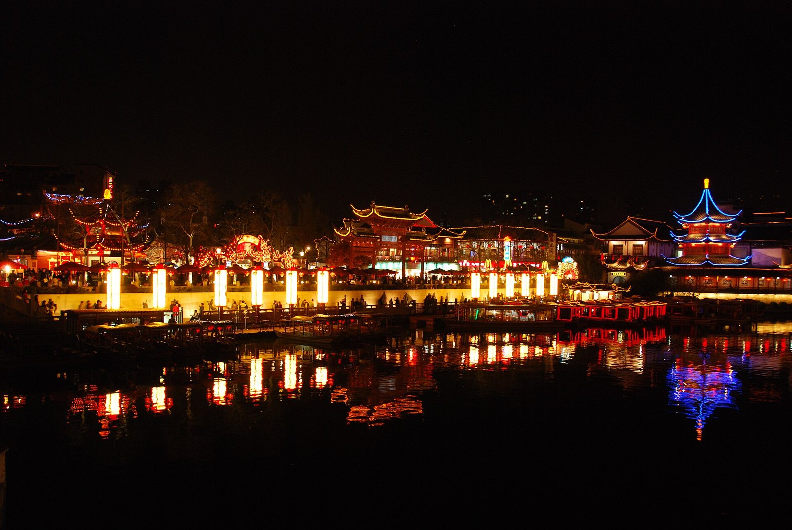 A night view of a Chinese river lined with traditional buildings and lanterns