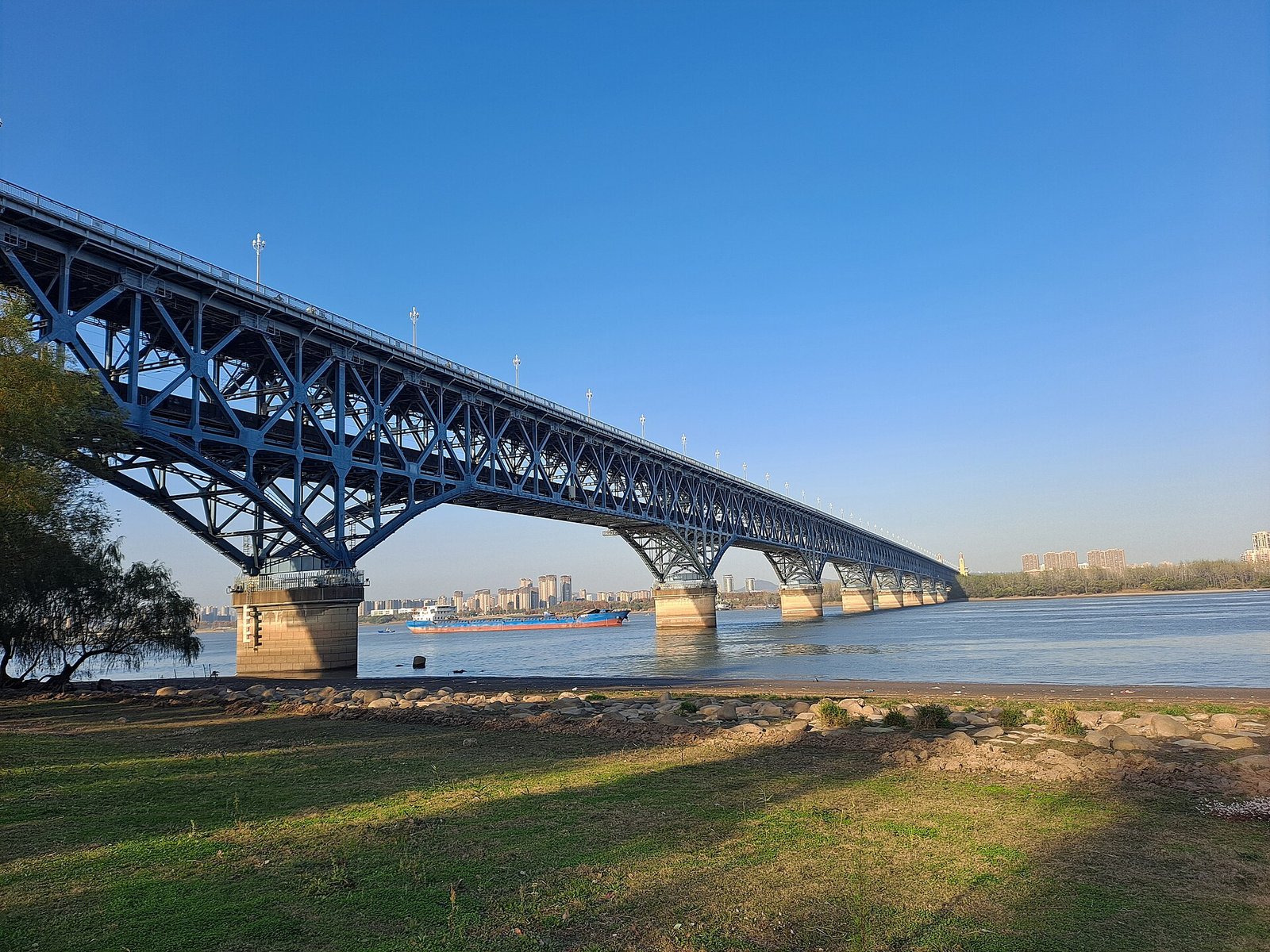 A long double-deck steel bridge with towers crossing a wide river