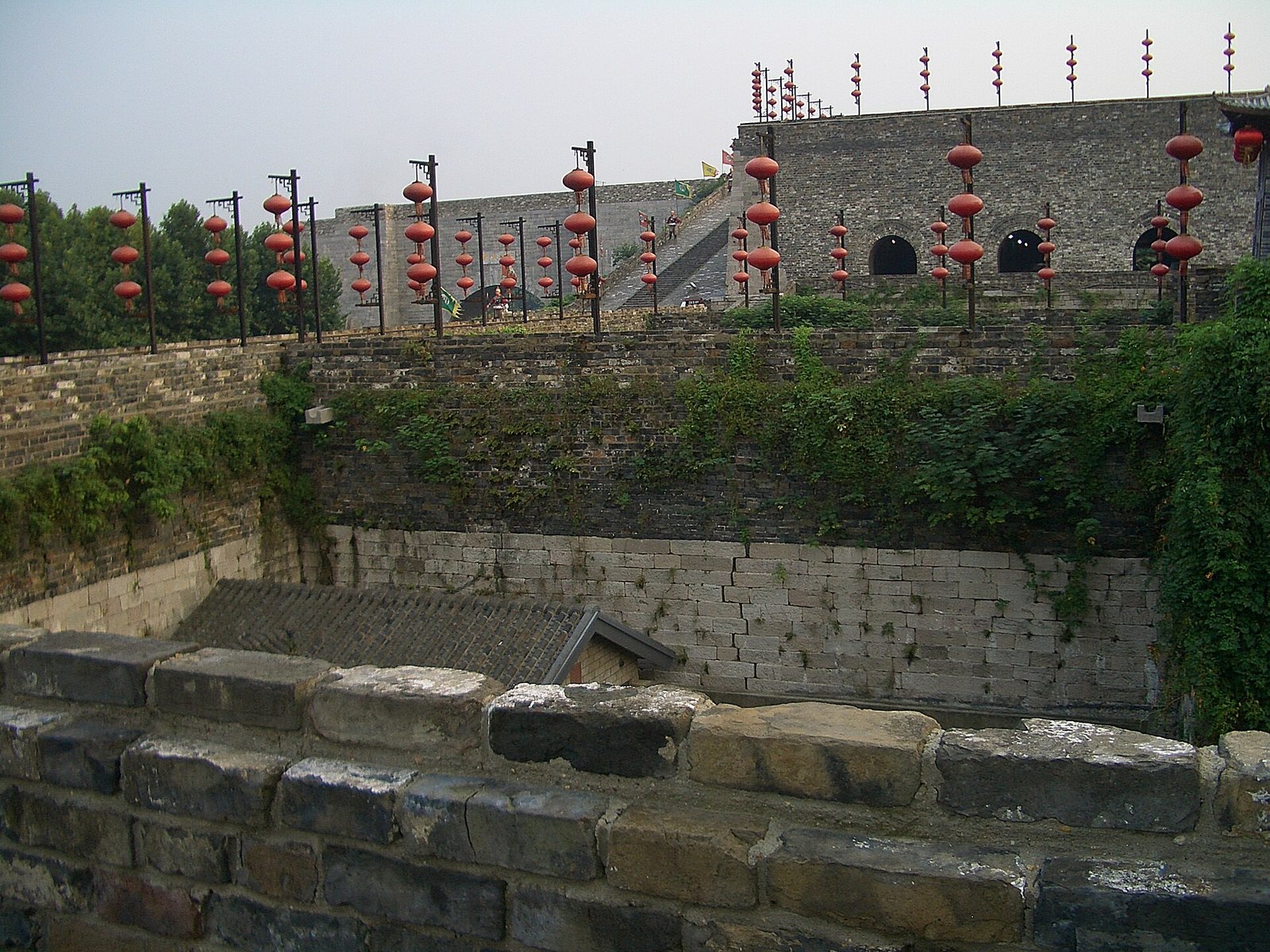 A long stretch of ancient grey-brick Chinese city wall hung with red lanterns