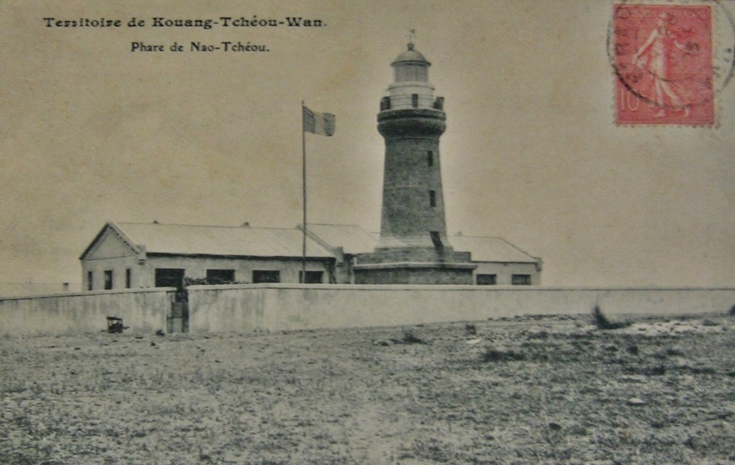 A sepia postcard captioned Territoire de Kouang-Tcheou-Wan, Phare de Nao-Tcheou, showing a stone lighthouse with a keeper’s cottage and a flagpole, with a red French stamp in the corner