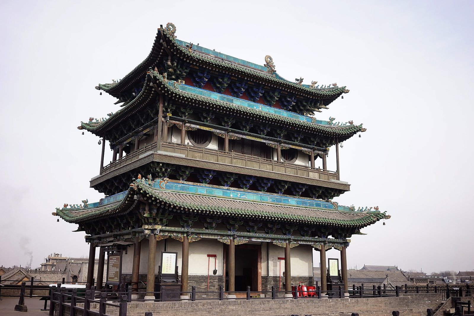 A tall multi-storey wooden tower on the Pingyao city wall, rising above the grey rooftops