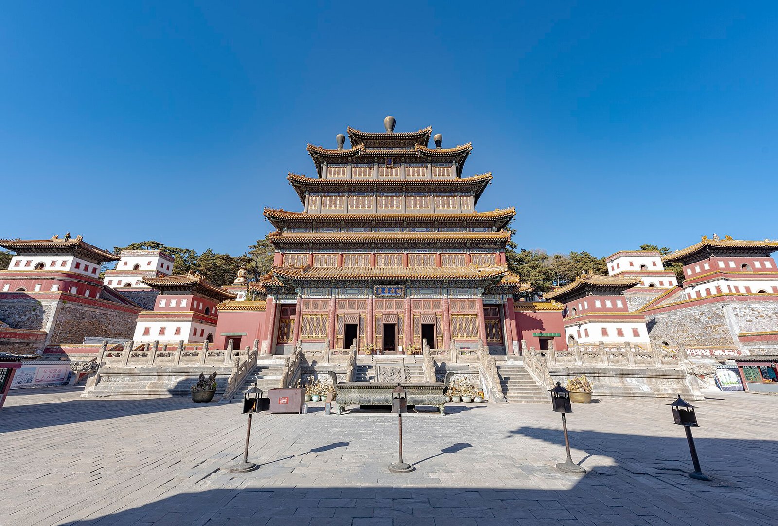 The tall multi-eaved Mahayana Hall at Puning Temple in Chengde, seen across a wide stone courtyard