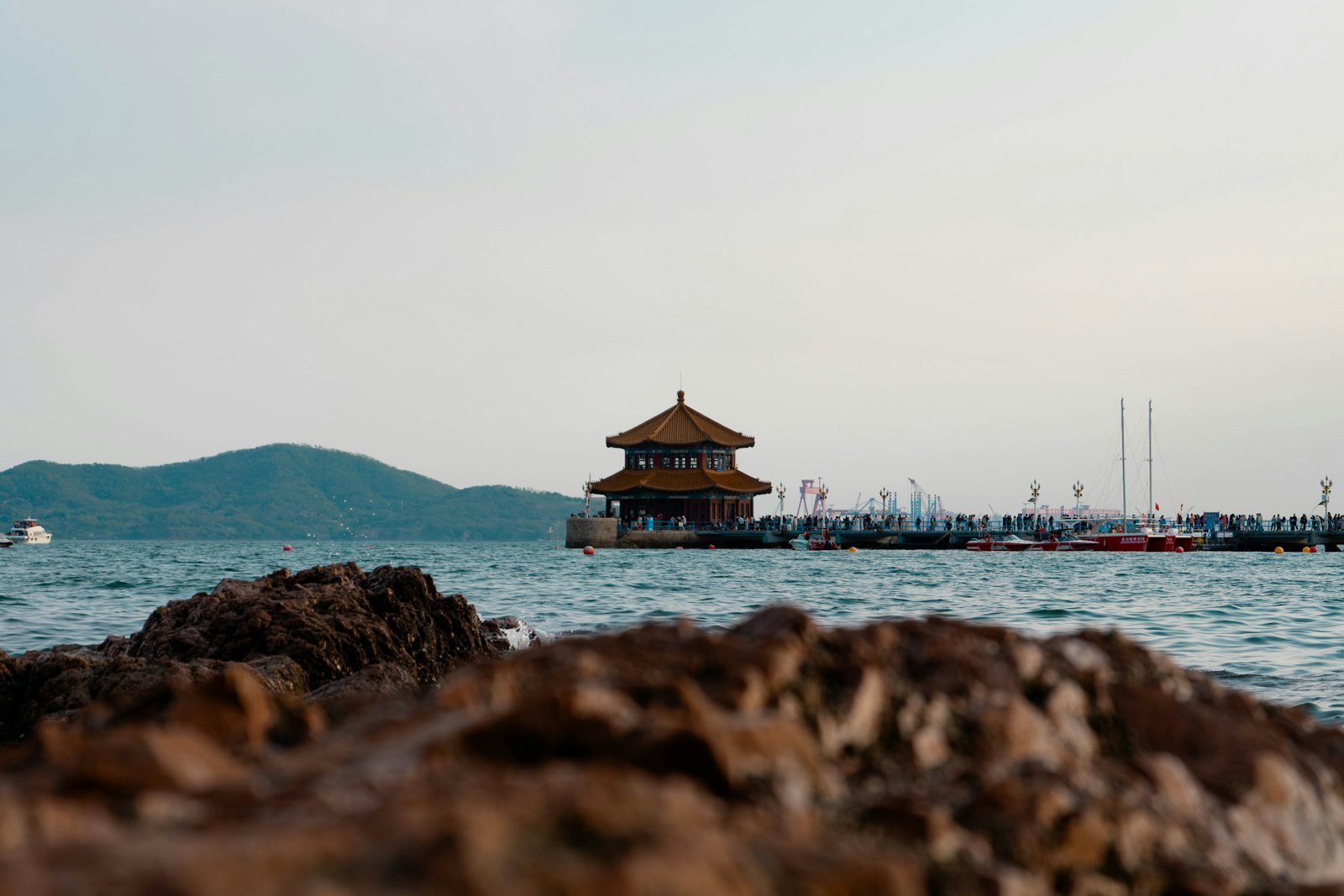 Zhanqiao Pier and its Huilan Pavilion extending into the sea at Qingdao, seen across the water from the rocks