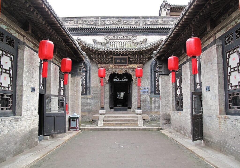 A grey-brick Chinese courtyard compound with tiled roofs and a stone gateway
