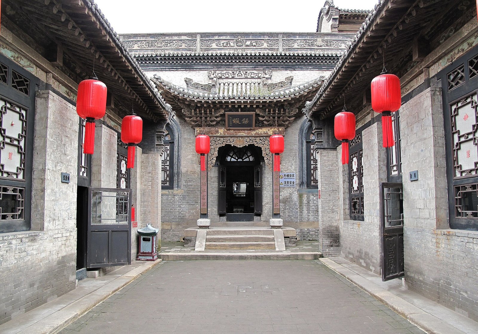 A grey-brick Chinese courtyard compound with tiled roofs and a stone gateway