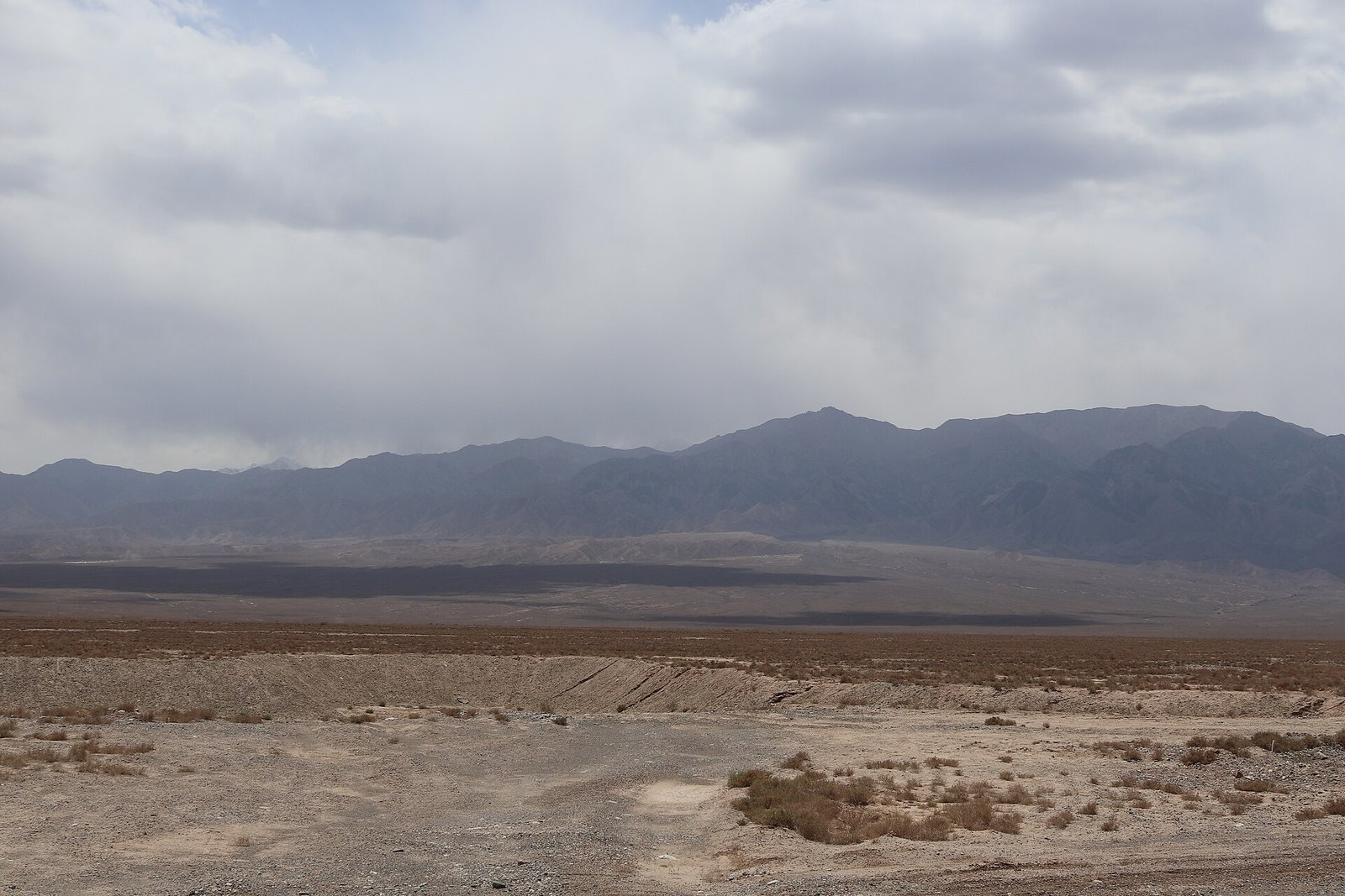The Qilian Mountains seen across a plain in Sunan County, Gansu, under a hazy sky
