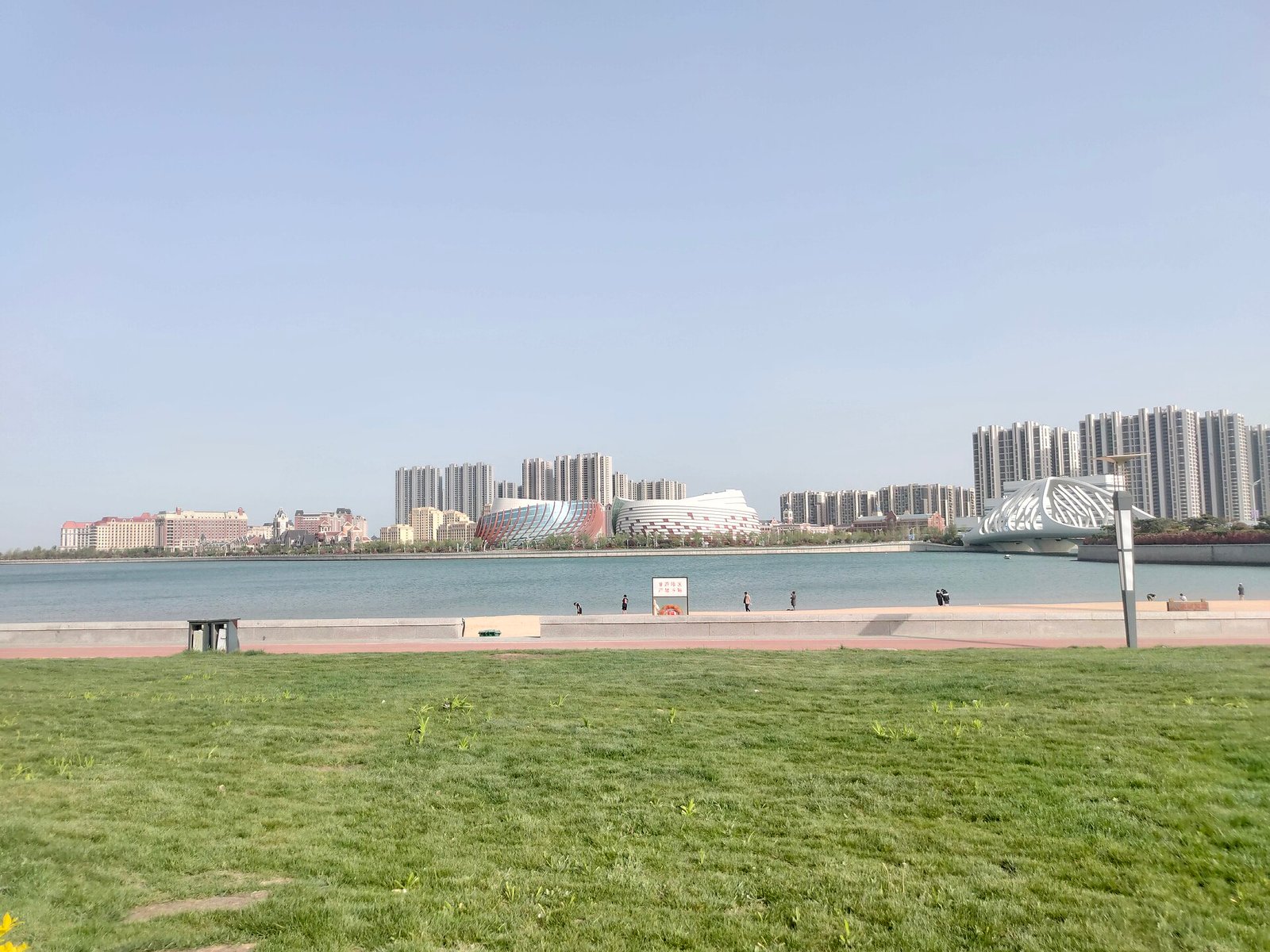 Low white buildings along a shoreline seen from the water, with a broad beach and a flat sea beyond