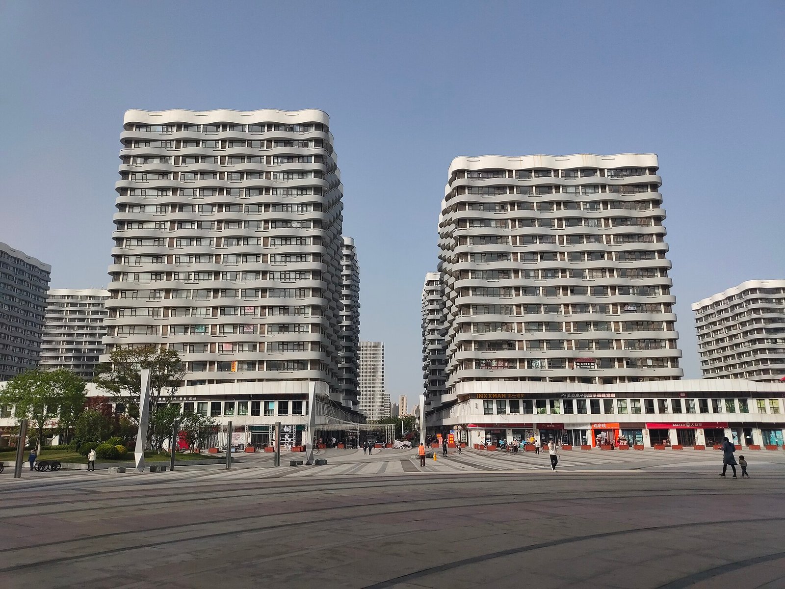 Two tall residential towers with regular window grids, seen from street level against a pale sky
