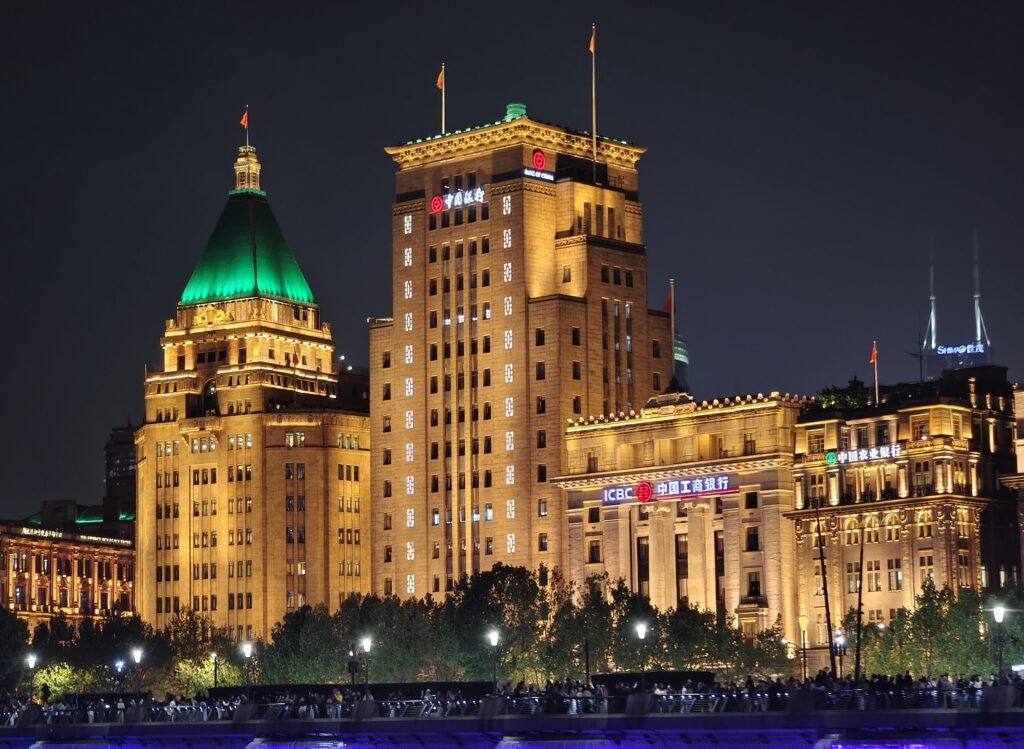 The historic Bund waterfront in Shanghai lit up at night, with the Peace Hotel's green pyramid roof on the left