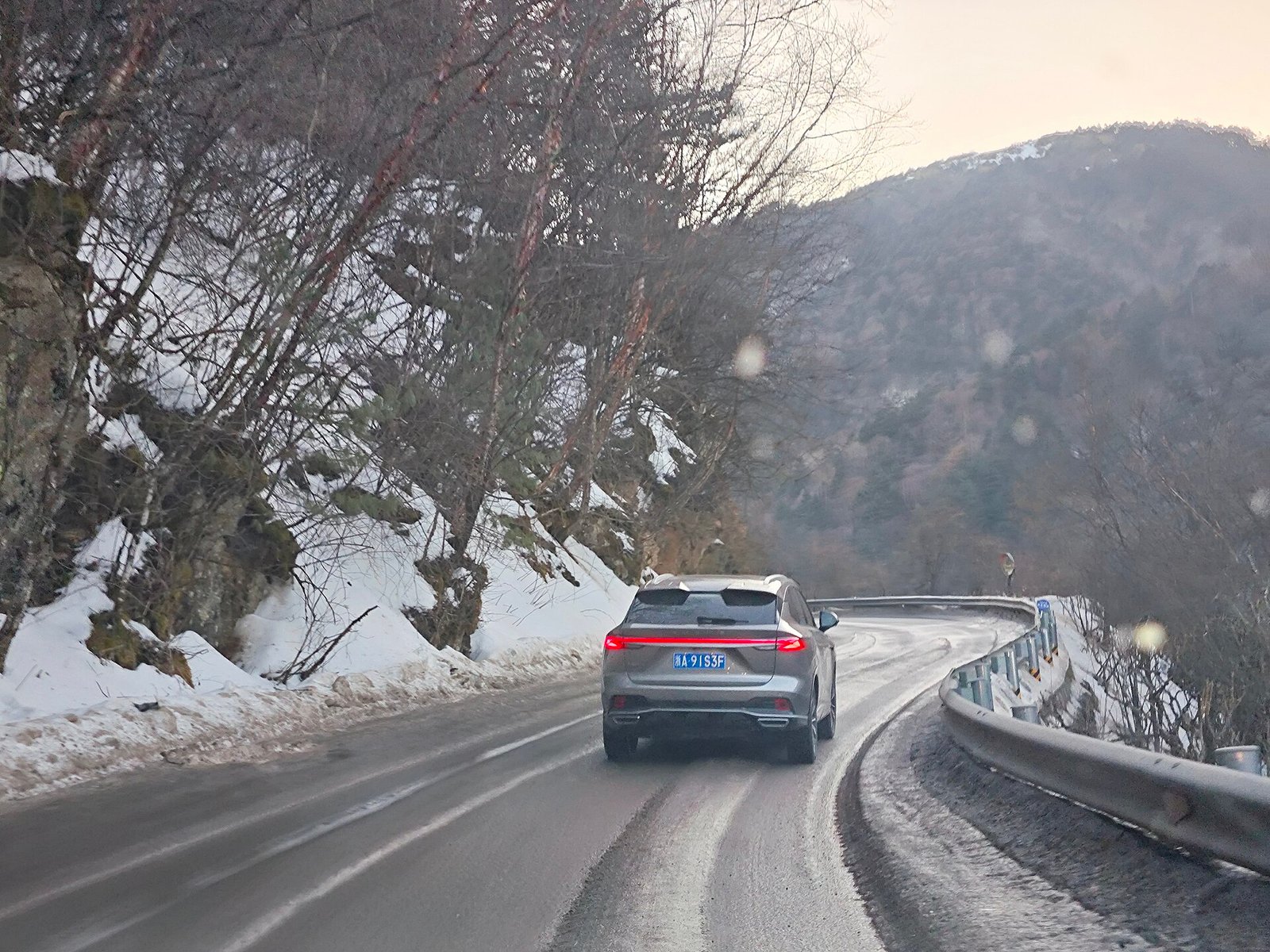 A car on a snow-covered mountain road on National Highway 347 through the Shennongding area of Shennongjia