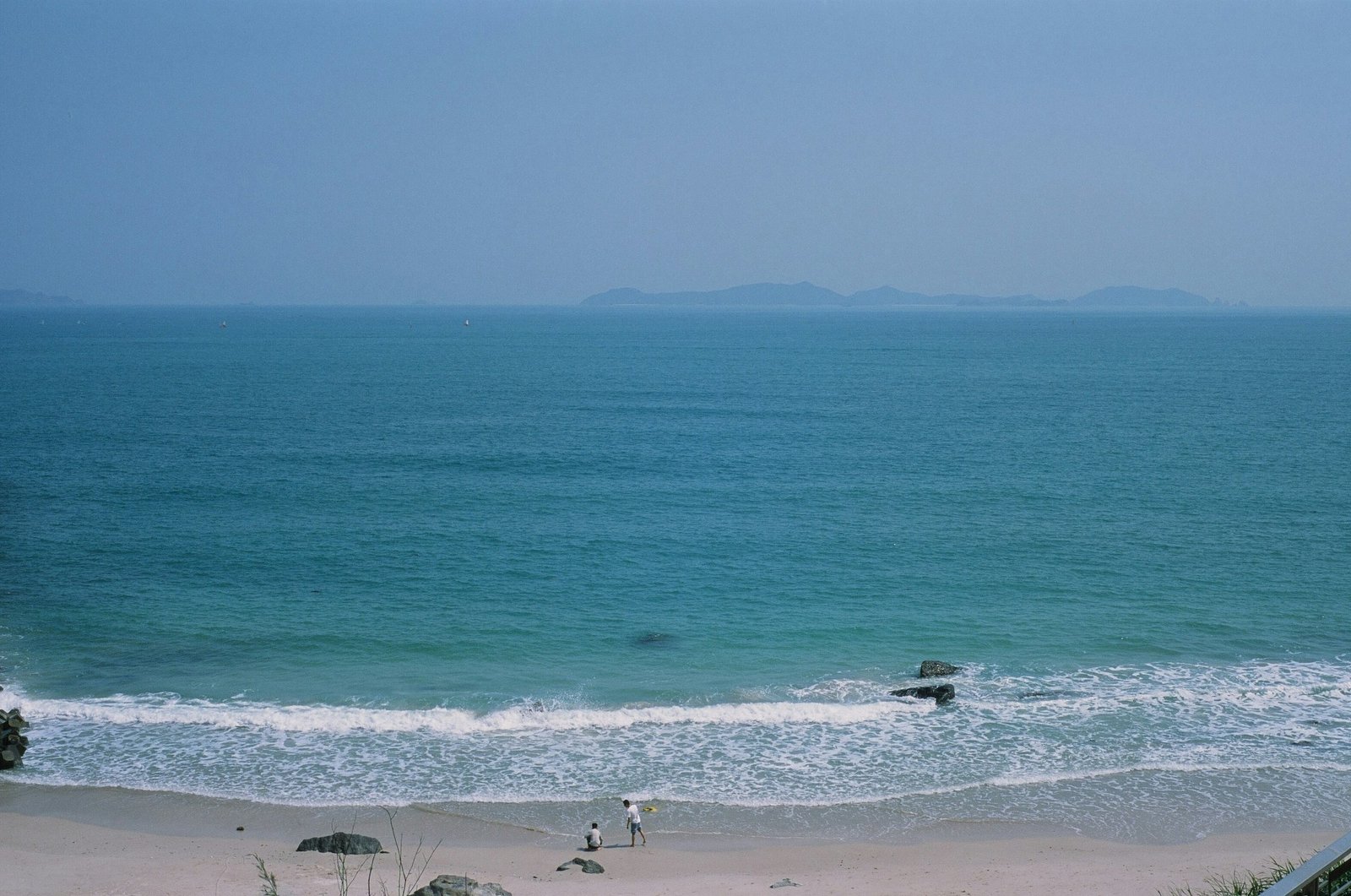Open sea and a sandy beach with small islands on the horizon