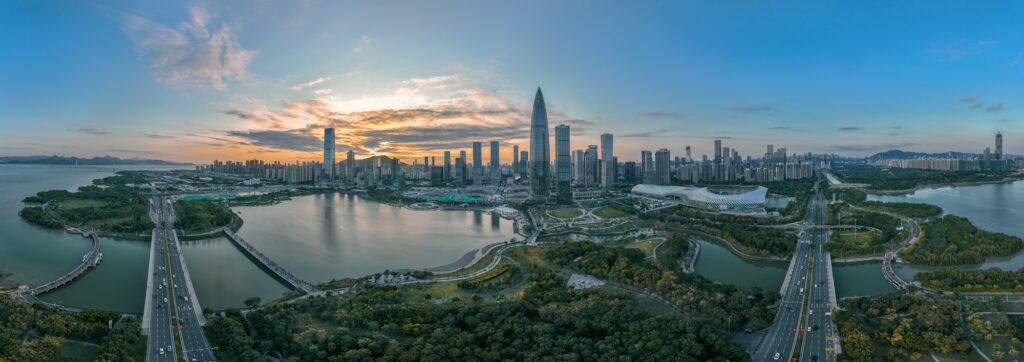Aerial panorama of Shenzhen Bay at golden hour, the mangrove park in the foreground and the towers of Futian rising behind