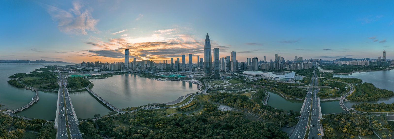 Aerial panorama of Shenzhen Bay at golden hour, the mangrove park in the foreground and the towers of Futian rising behind