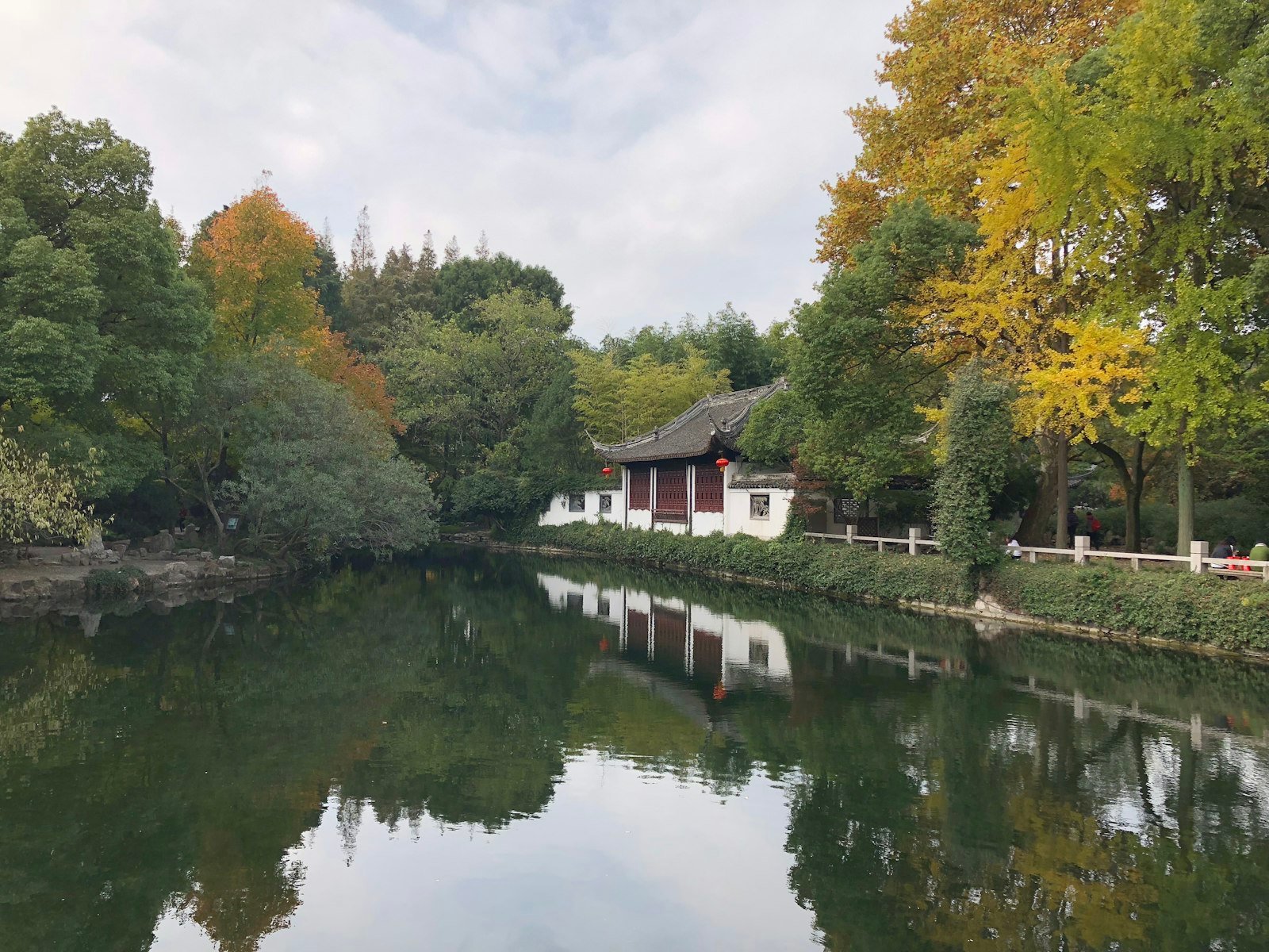 A Chinese classical garden pavilion with upturned eaves reflected in a pond