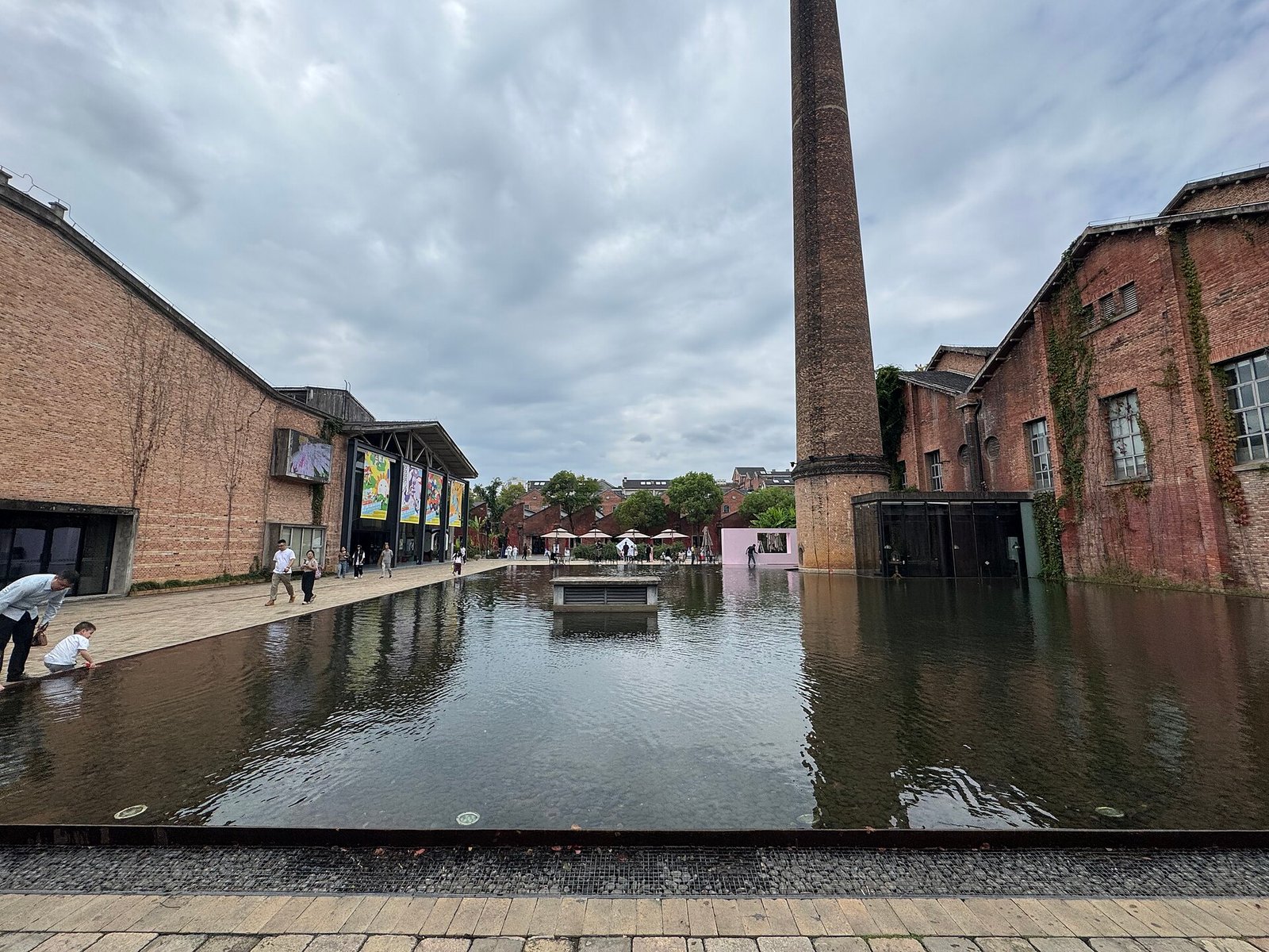 A brick chimney and former factory buildings reflected in a pool of water at Taoxichuan, Jingdezhen